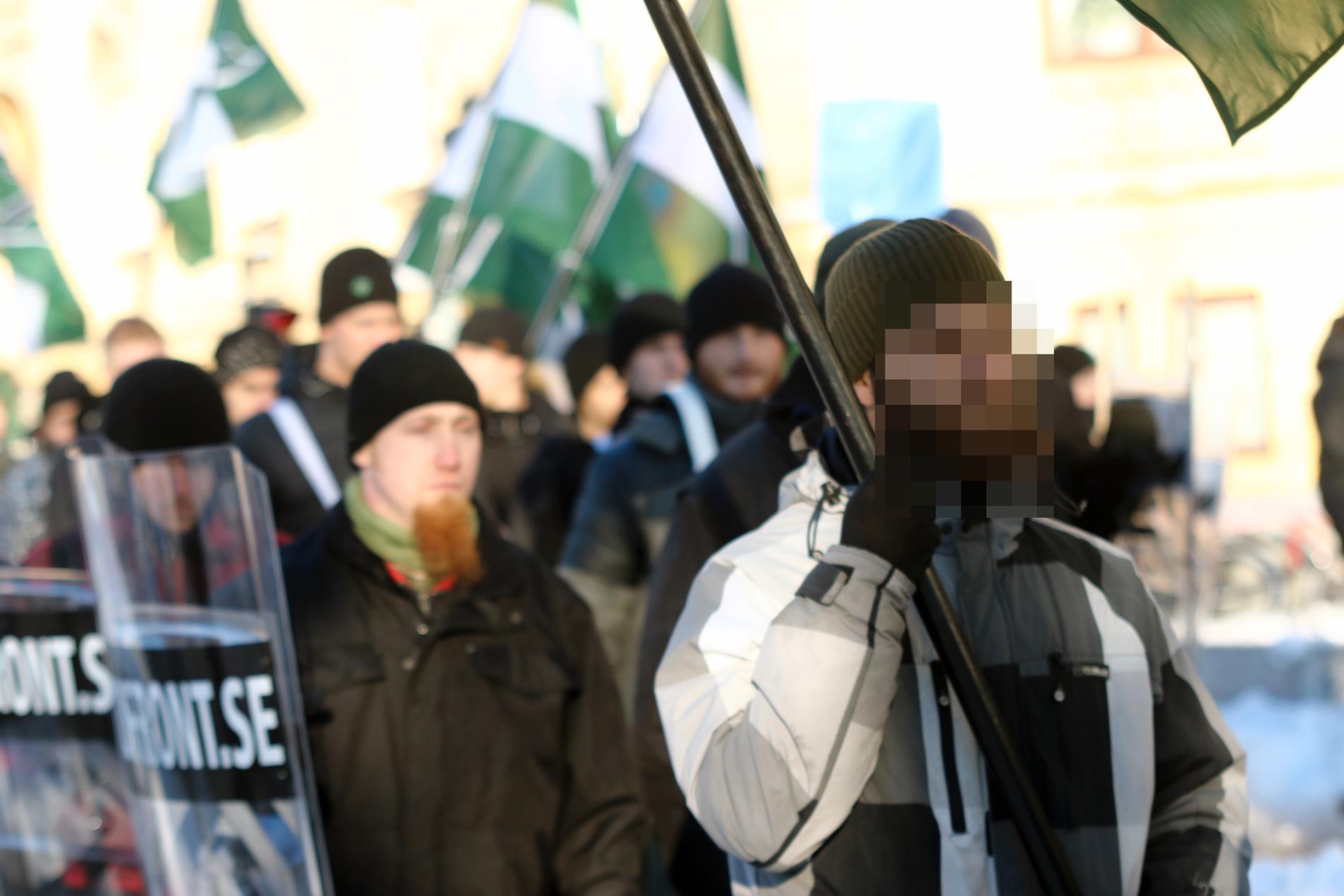 Den misstänkte 23-åringen bär flaggan. Aftonbladet har valt att inte visa ansiktet på de misstänkta bombmännen före fällande dom. 