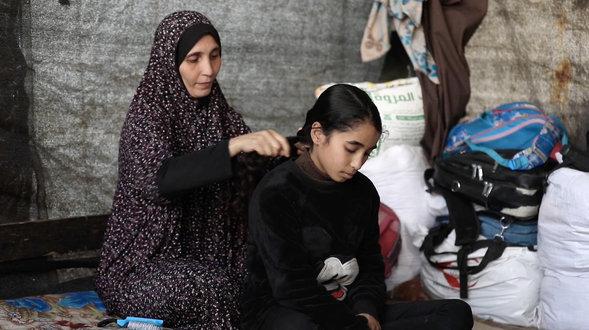 Mamma Nadia flätar dottern Shahads hår. Tolvåringens fyra syskon dödades i en flygattack mot norra Gaza.