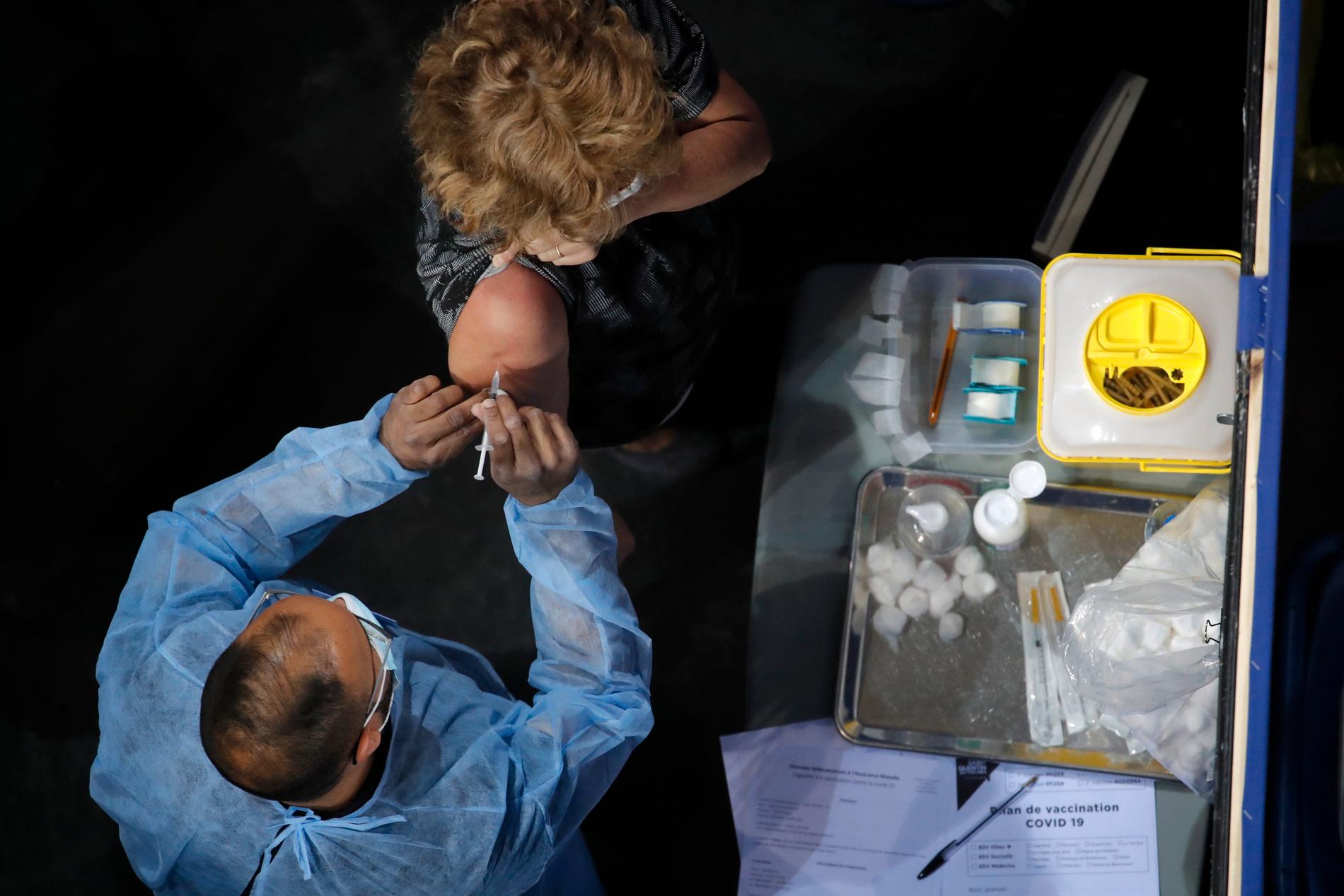 En kvinna får sin vaccinspruta på ett vaccinationscenter i Saint-Quentin-en-Yvelines, väster om Paris.