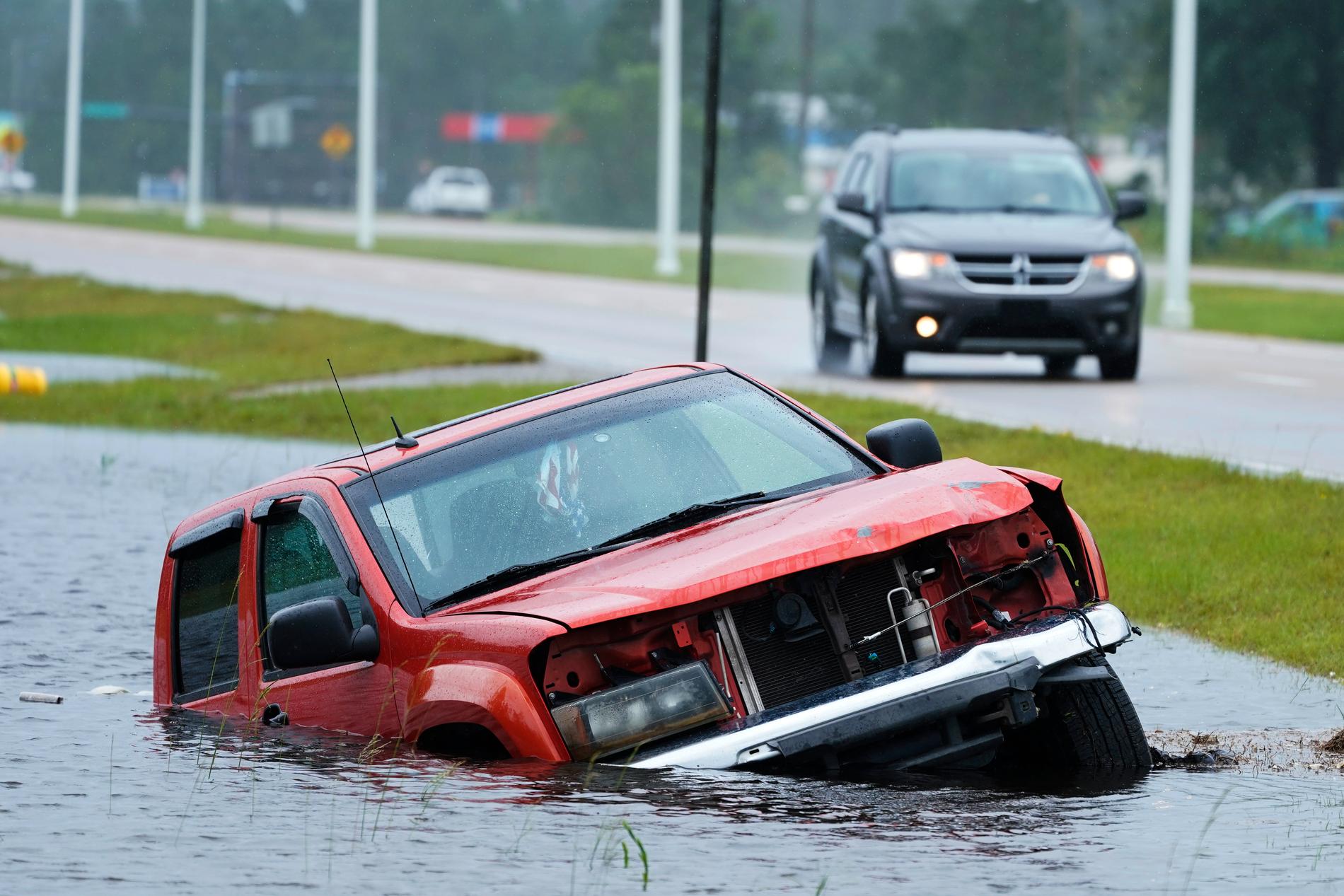 Ett övergivet fordon halvt sänkt bredvid en nära översvämmad motorväg.