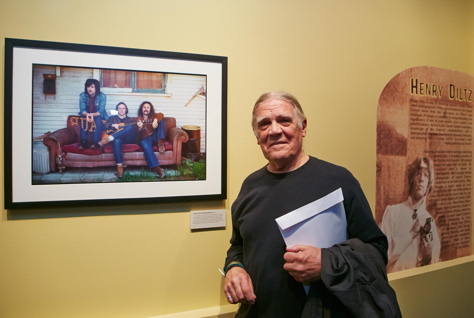 Henry Diltz bredvid sitt ikoniska fotografi som blev omslaget till Crosby, Stills & Nash debutalbum 1969, i utställningen "California Dreamin': The Sounds of Laurel Canyon, 1965 - 1977," på Grammy Museum i Los Angeles 2014.