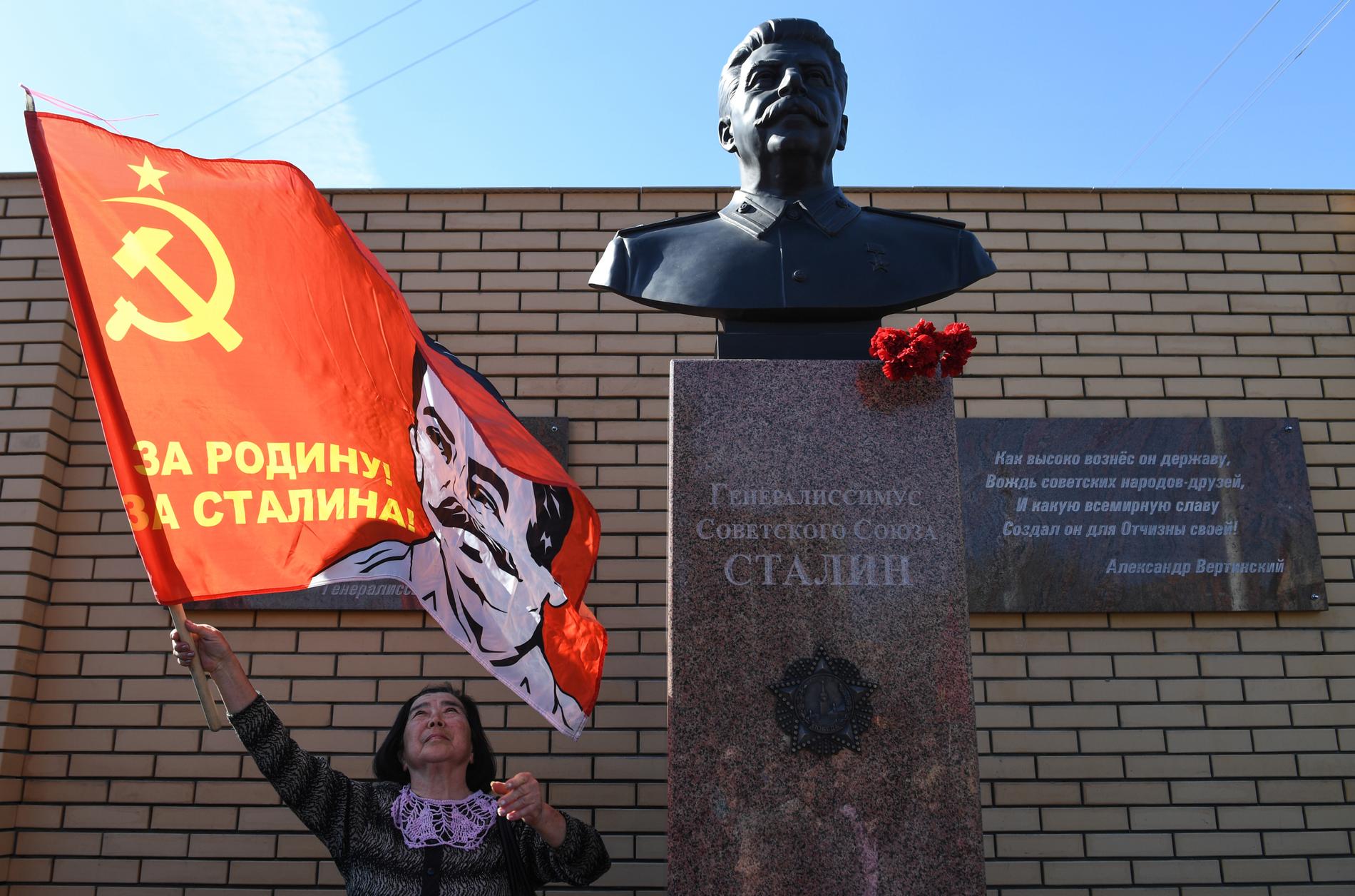 En kvinna håller i en flagga med texten ”För fosterlandet, för Stalin” vid invigningen av statyn i Novosibirsk.