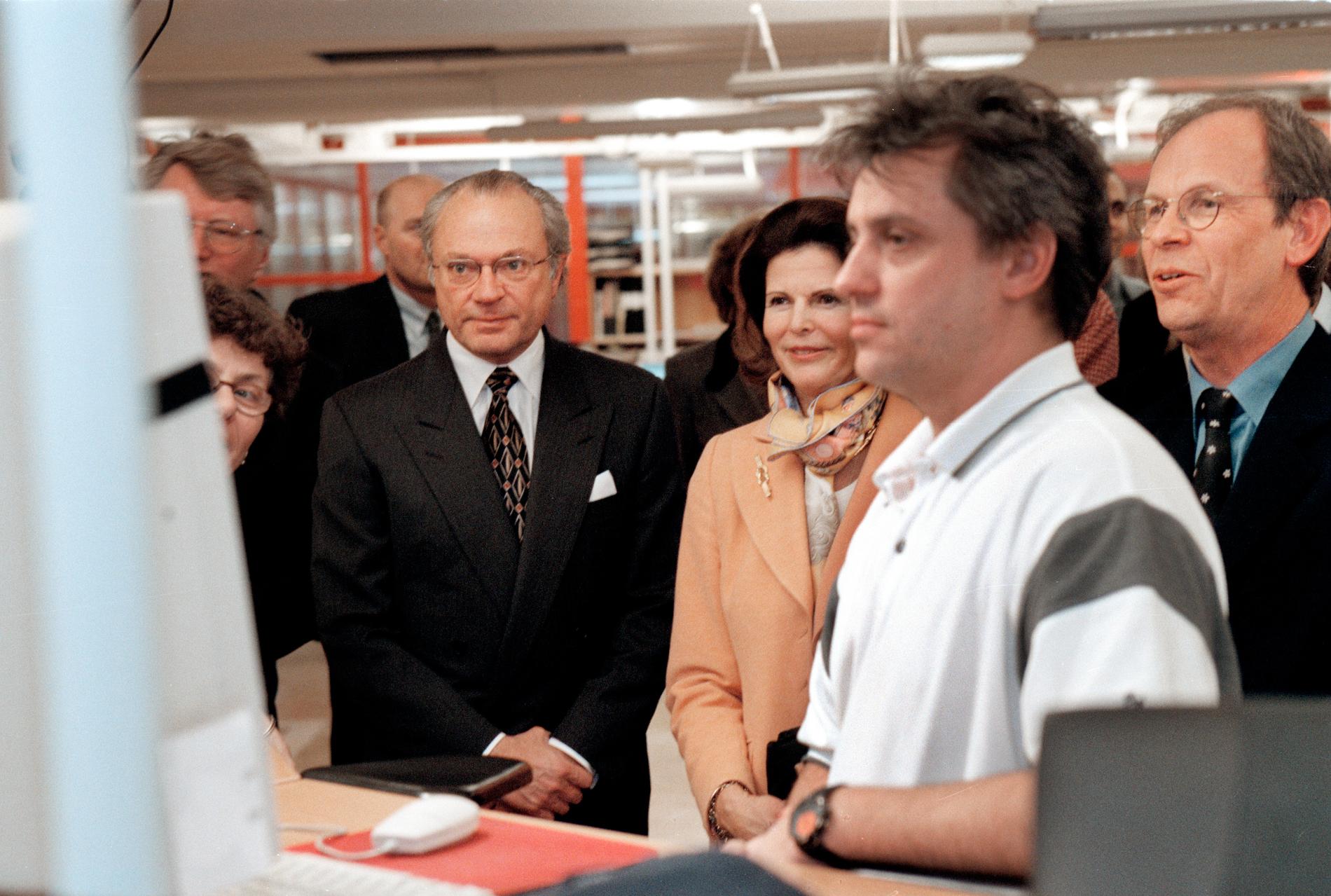 Kung Carl XVI Gustaf och drottning Silvia på besök på webbredaktionen, år 2000. De ser på när Mikael ”Micke” Andersson jobbar. 