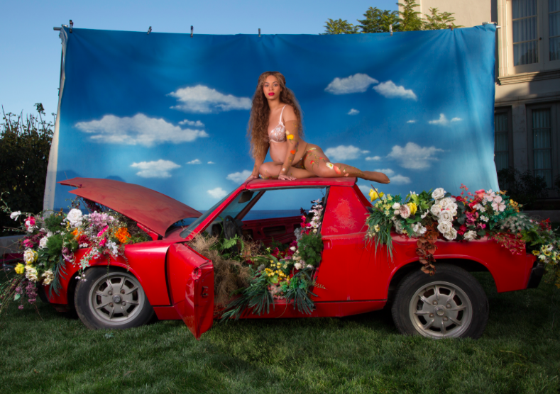 Beyoncé firar tvillingmagen med att posera på en röd bil. Varför förklaras inte på hennes sajt.