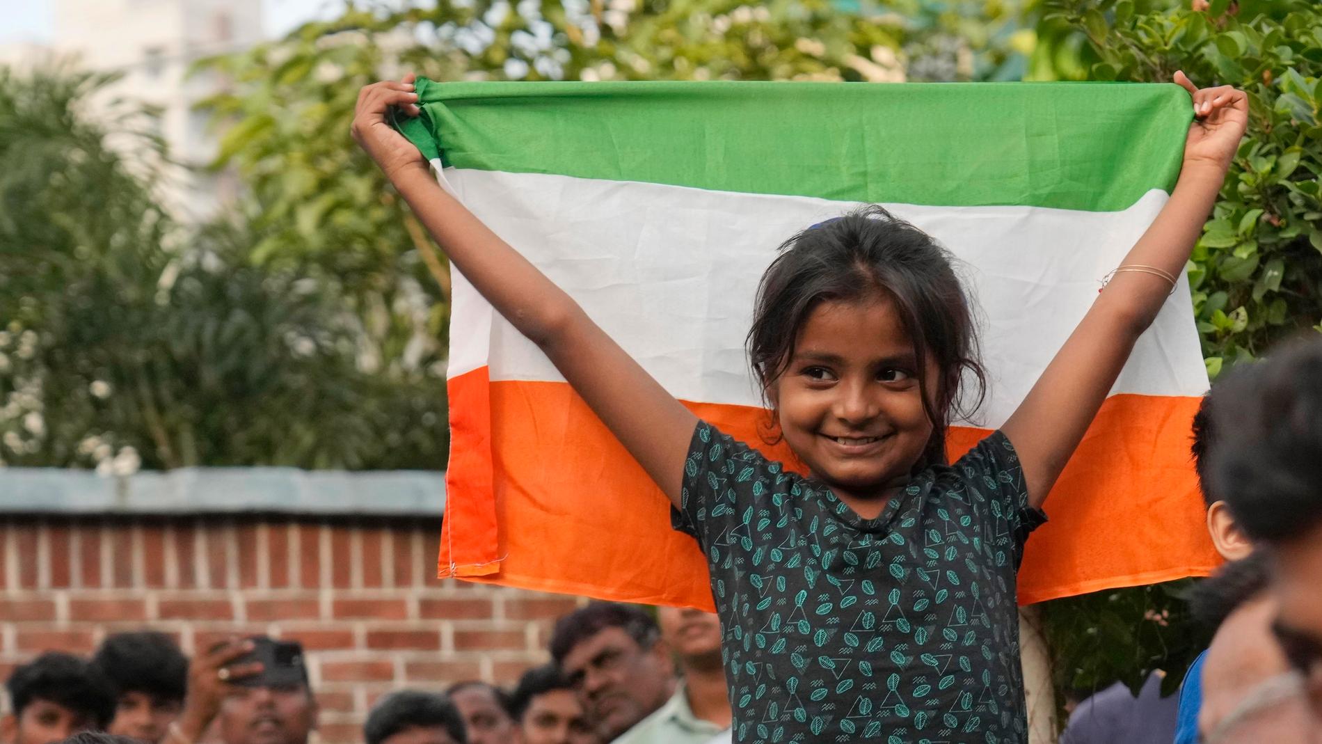 En flicka firar landningen på månens sydpol med en indisk flagga.