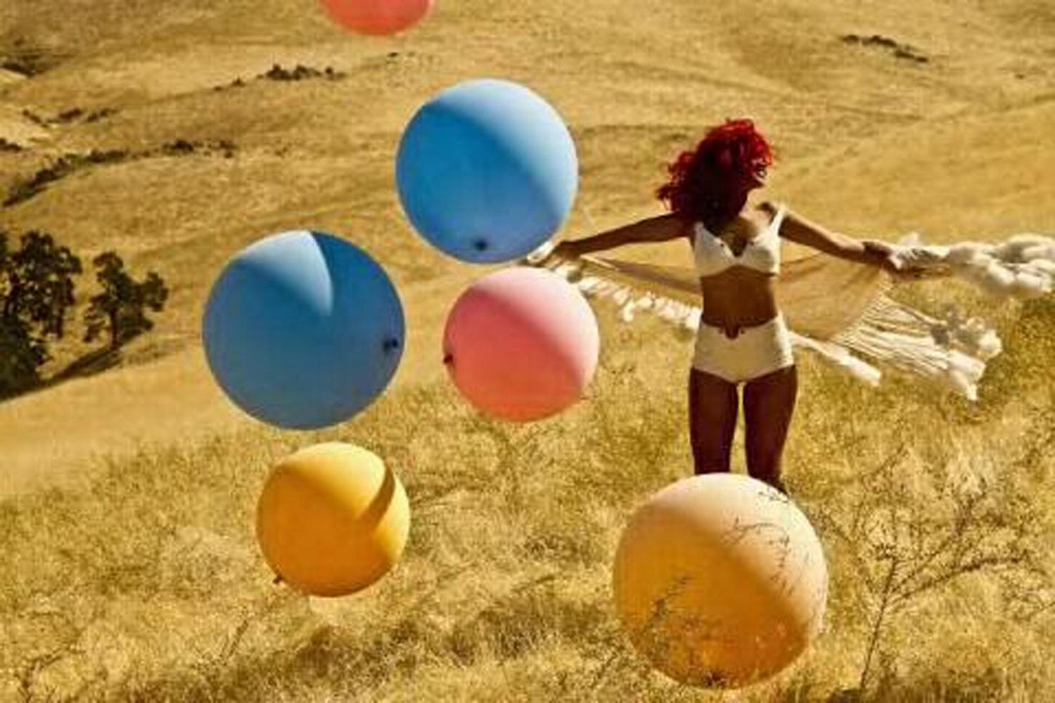 Rihanna lugnar ned sig i gräset bland ballonger.