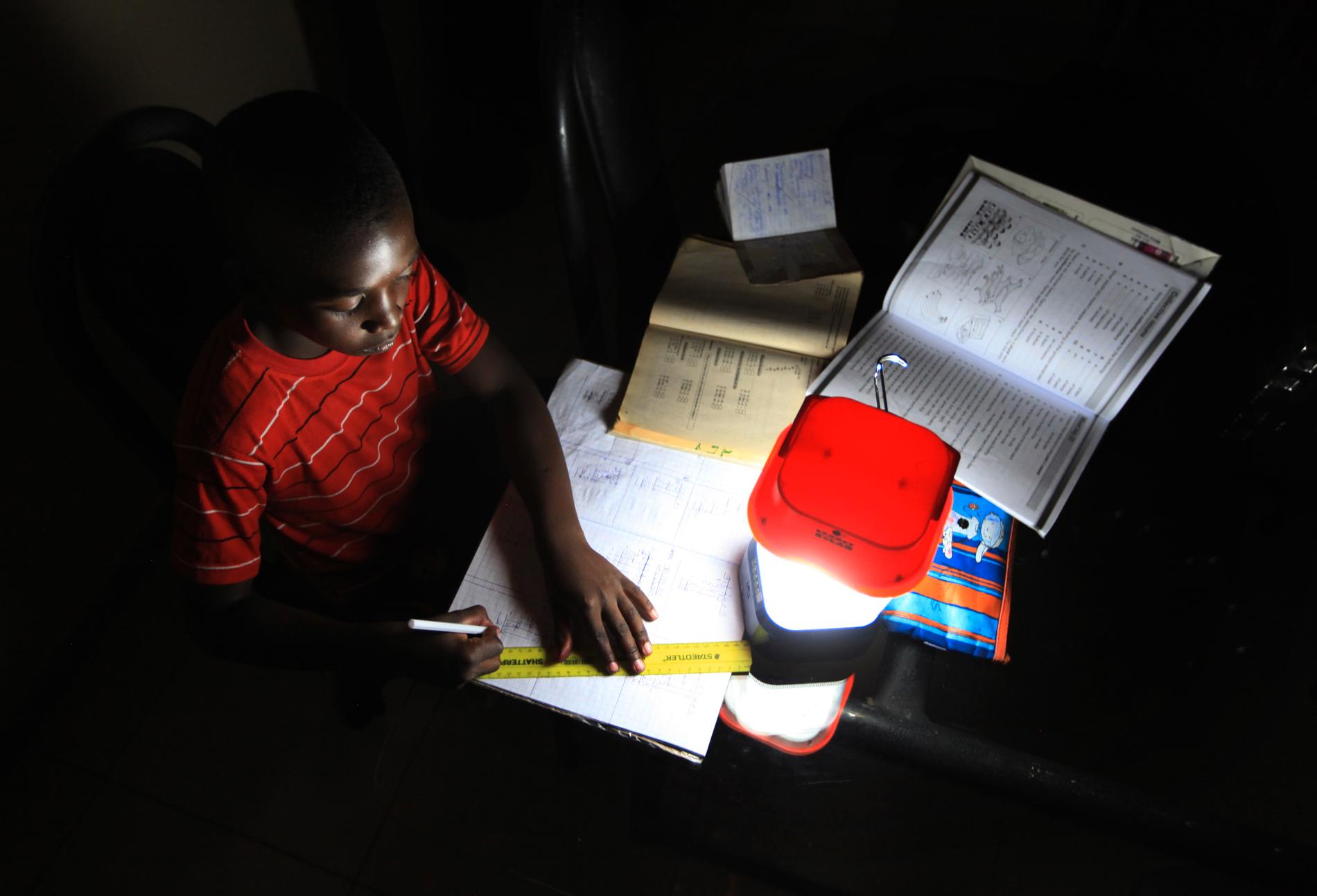 En pojke gör läxor under en solladdad lampa i Zimbabwes huvudstad Harare. Arkivbild, som inte direkt har med BGFZ att göra.