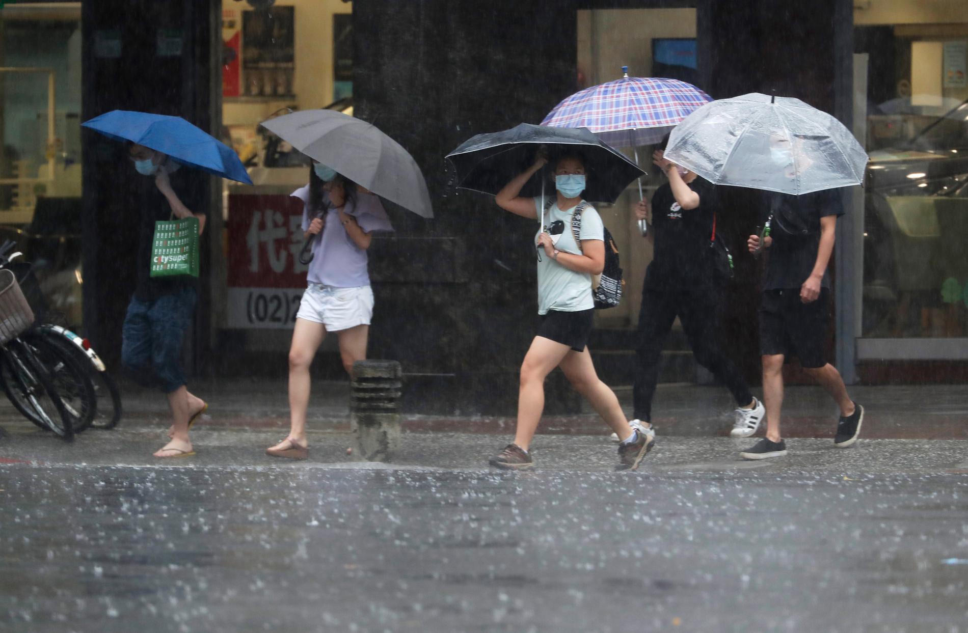 Folk med paraplyer i Taiwans huvudstad Taipei tar skydd undan skyfall efter tyfonen Chanthus framfört på ön under helgen.