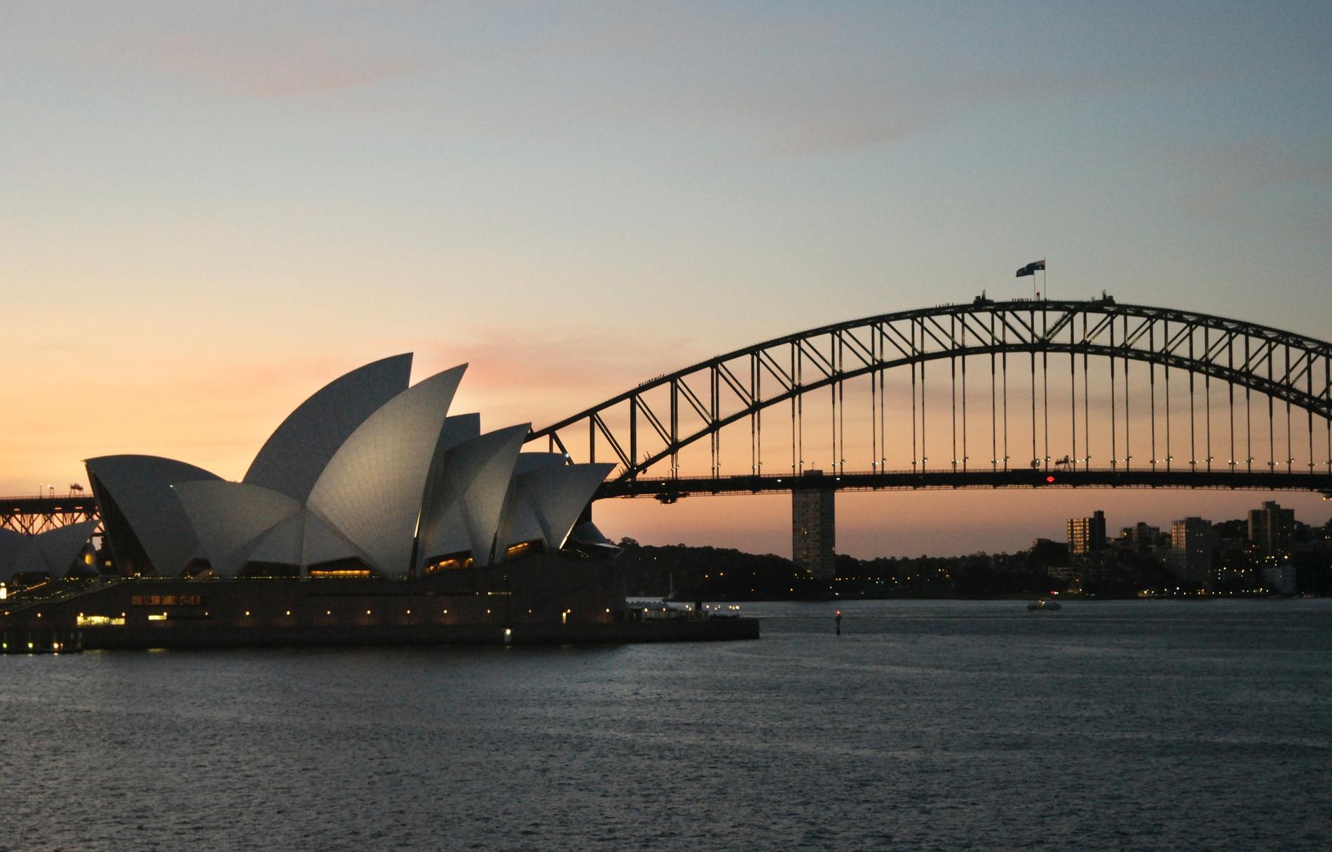 Operahuset i Sydney i sällskap av Harbour Bridge och en magisk solnedgång.