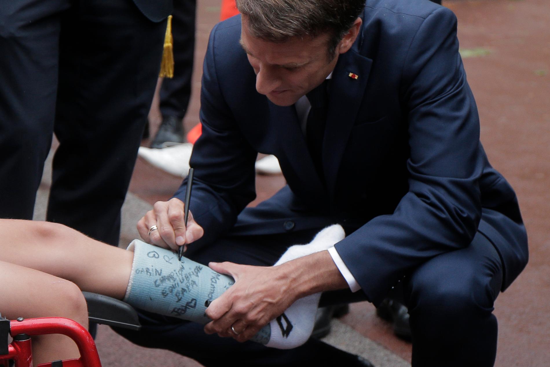 Frankrikes president Emmanuel Macron signerar en pojkens bengips innan han röstar söndagen den 19 juni 2022 i Le Touquet, norra Frankrike. 