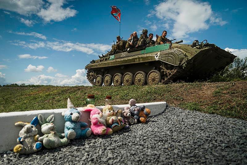 Ryssland-lojala separatister kör förbi en minnesplats för offren i MH17-katastrofen i östra Ukraina den 16 juli.