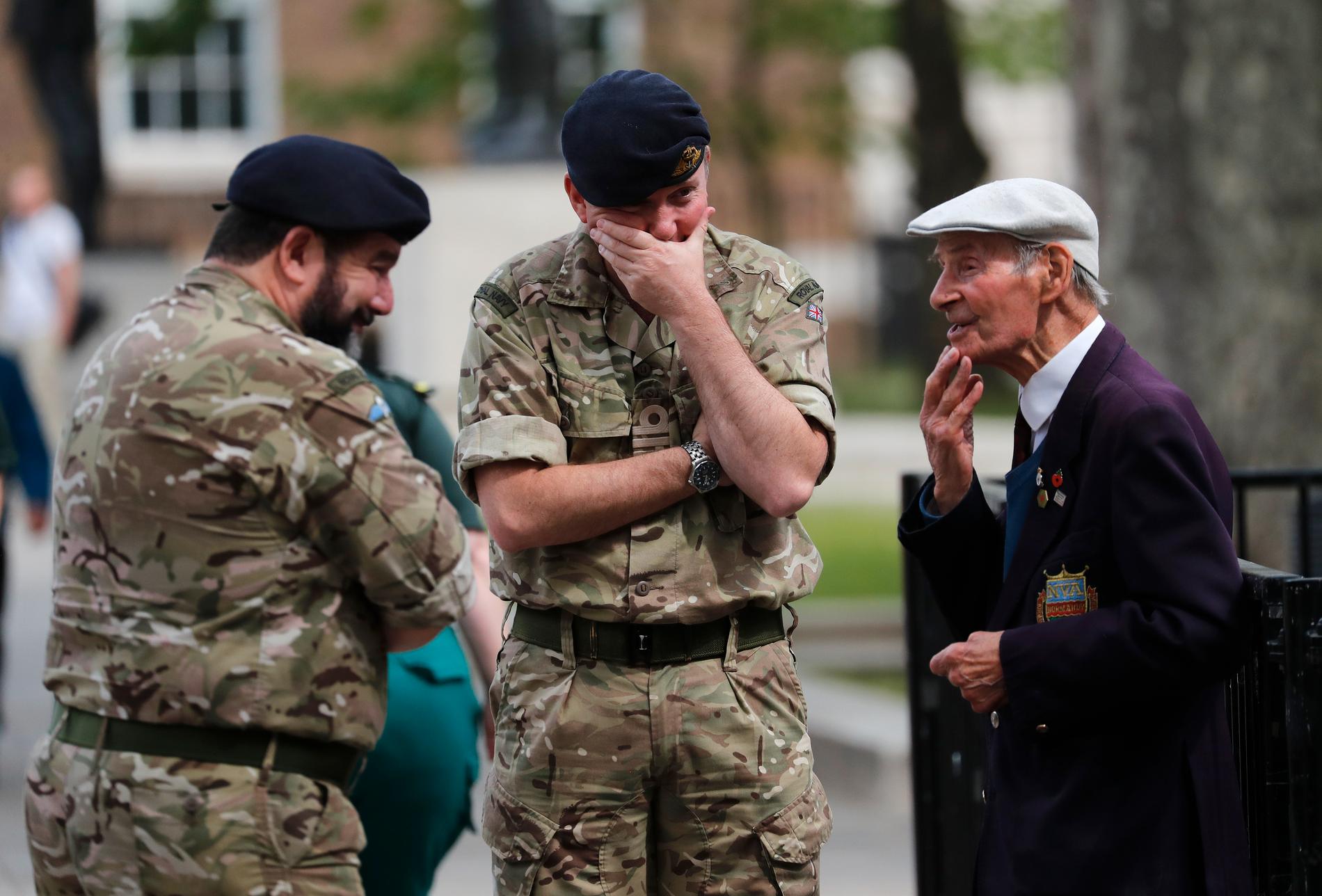 En krigsveteran (till höger) talar med yngre kollegor, efter två minuters tystnad på Whitehall i London.