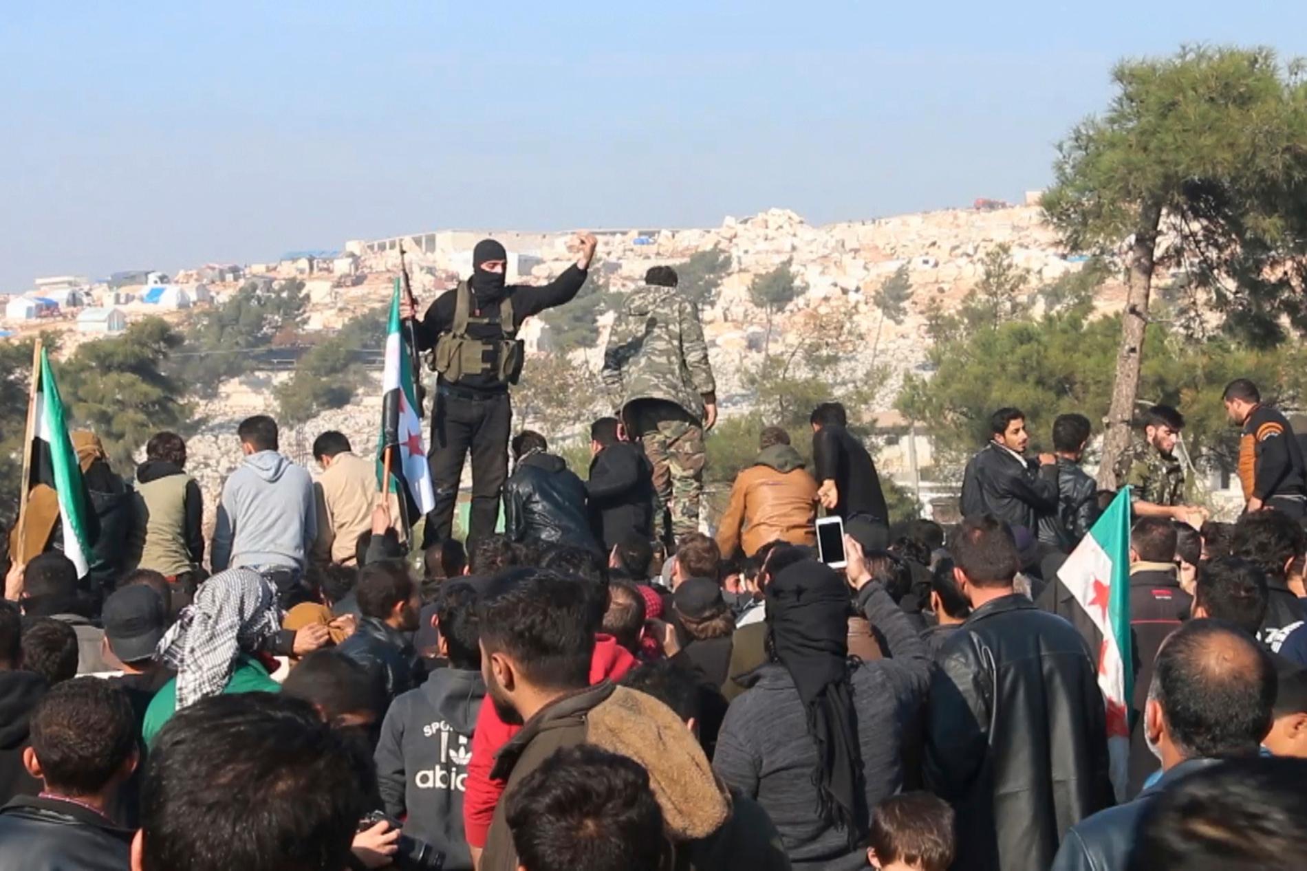 Stridande från jihadistalliansen Hayat Tahrir al-Sham försöker skingra en folkmassa som protesterar mot regeringssidans flyganfall i Idlib. Arkivbild från den 20 december.