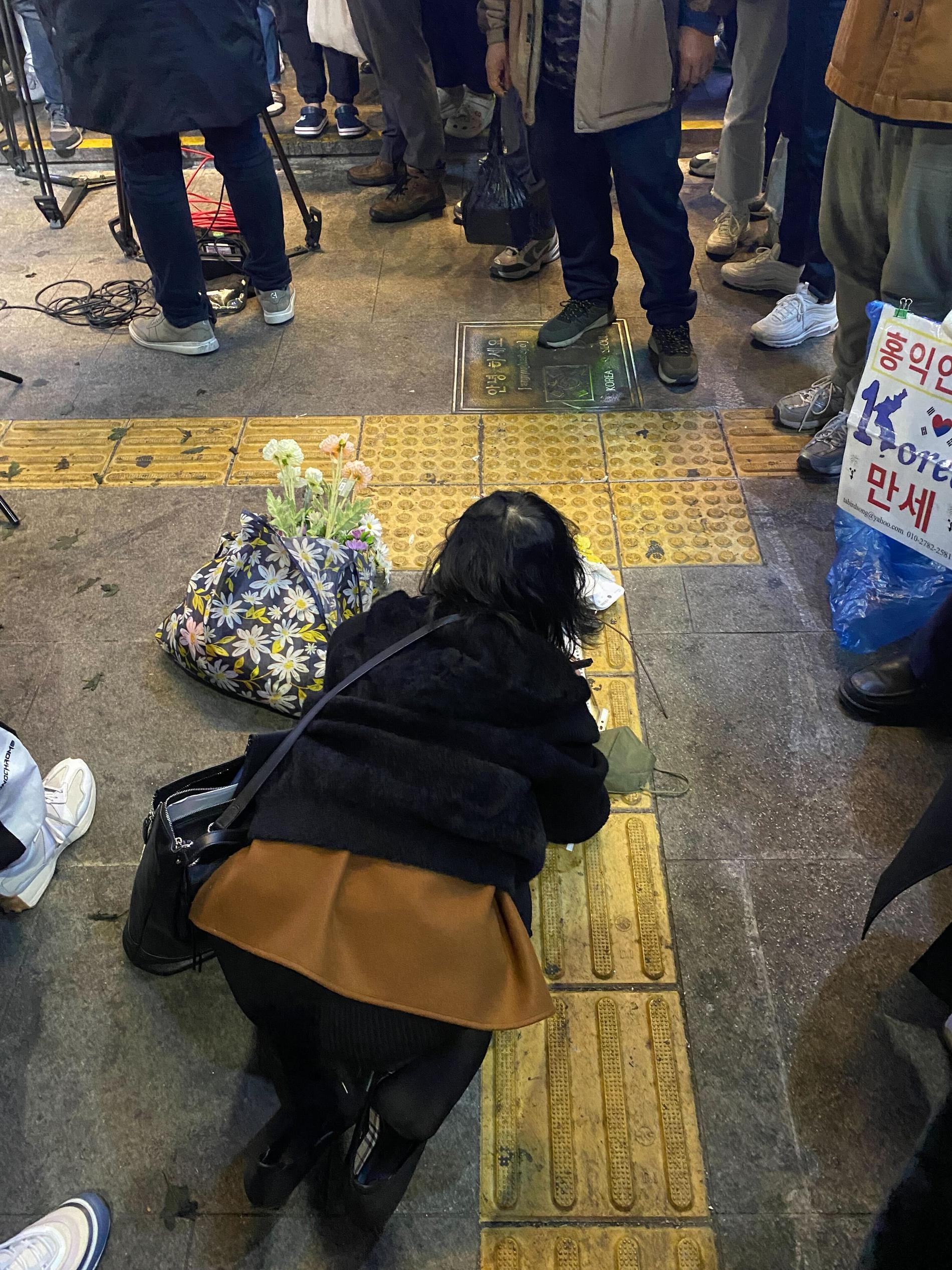 En kvinna faller ner på knä vid platsen och gråter.