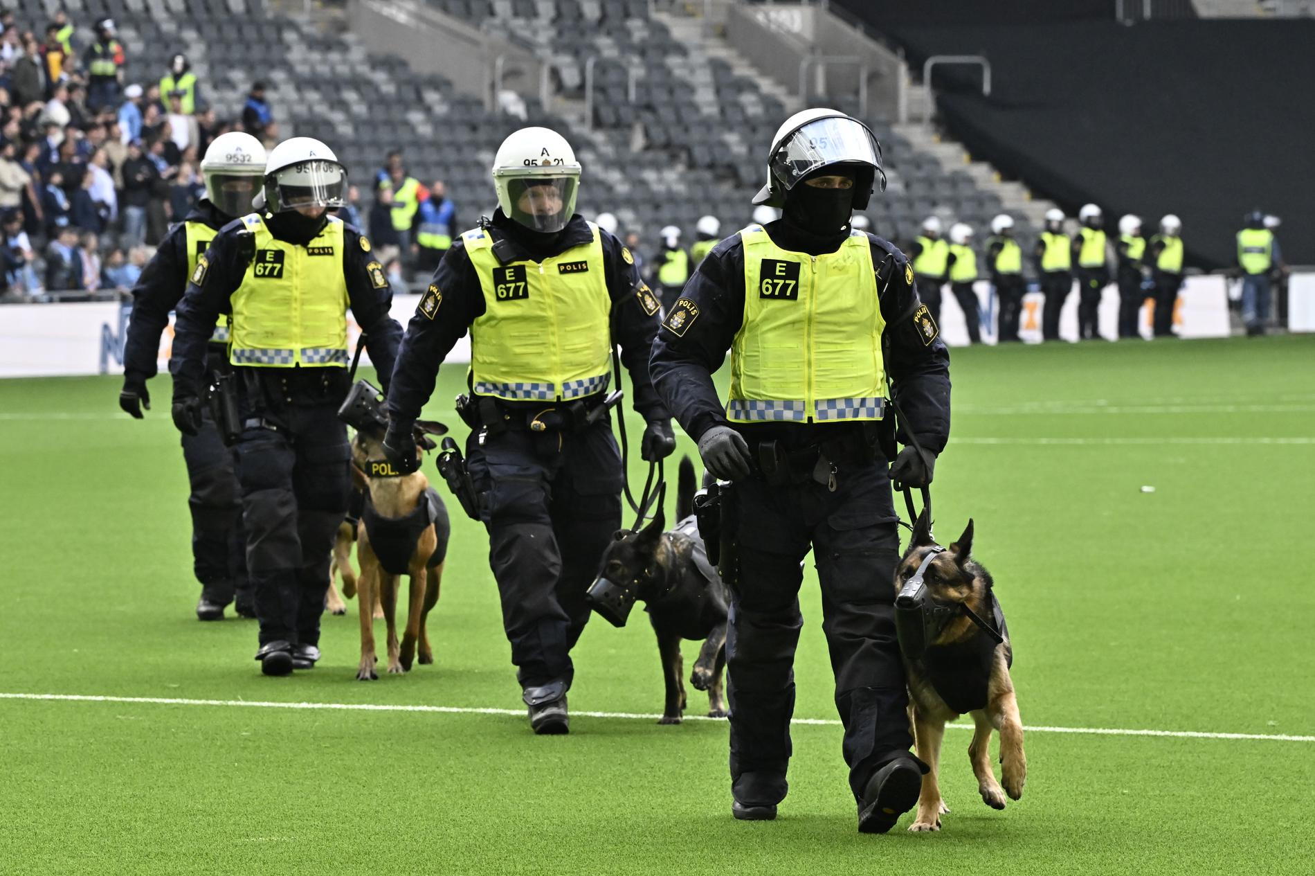 Poliser med hundar och kravallutrustning lämnar planen under söndagens fotbollsmatch i allsvenskan mellan Djurgården och AIK på Tele2 arena i Stockholm.
