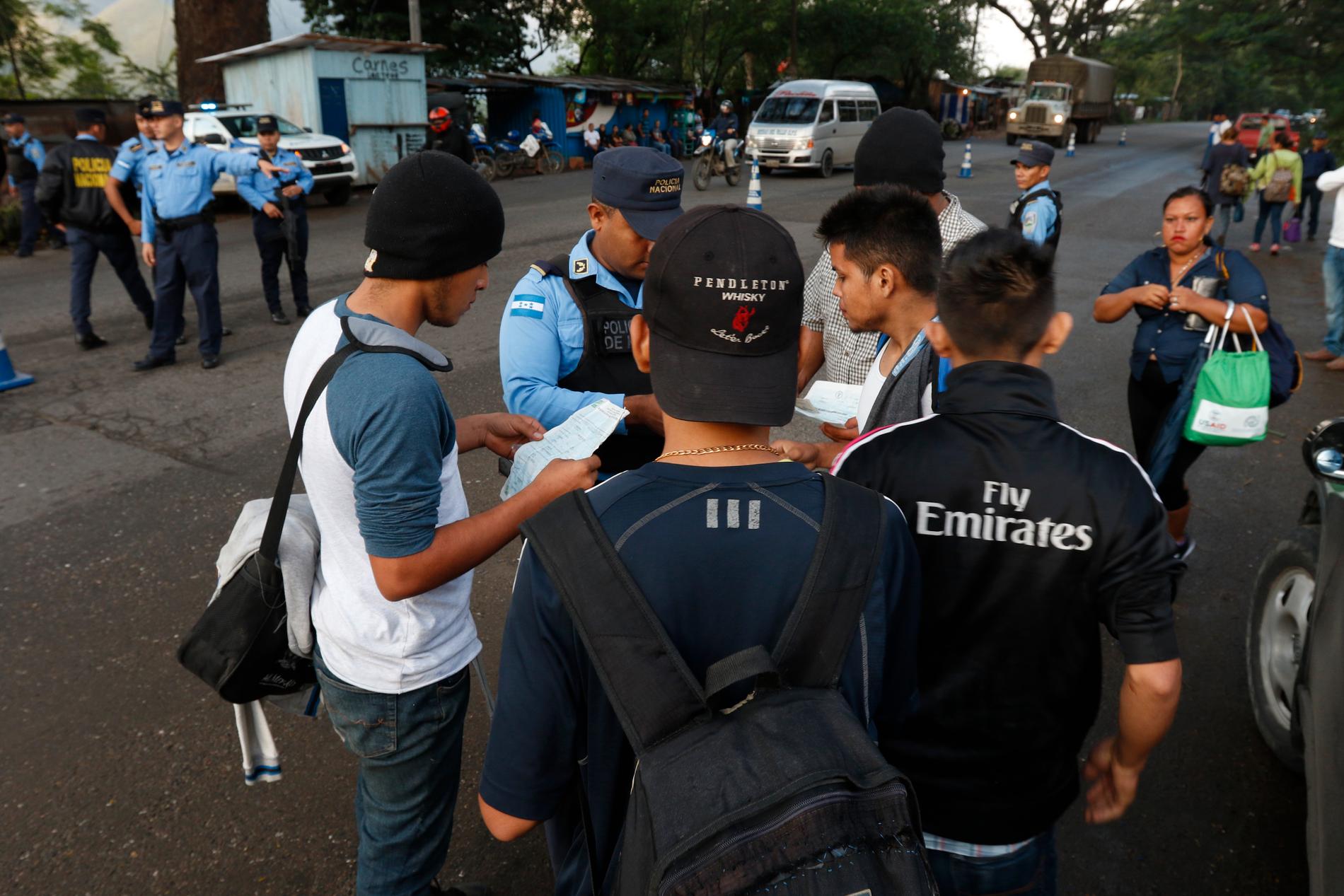 Lokal polis kontrollerar migranters dokument när de tidigt på morgonen passerar Cofradìa i Honduras på väg mot USA. Bilden är från den 15 januari 2019.