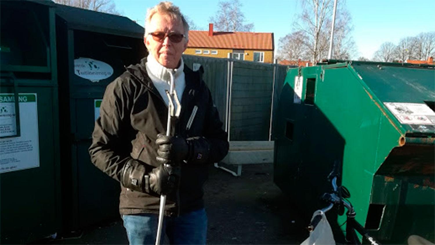 Kåre Eriksson med hjälpmedlet han använder för att fiska upp burkar ur containrar. Han cyklar 1,5 mil om dagen. Pantburkarna lägger han i kassar som hänger på styret. 