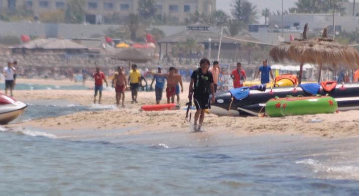 Här syns skytten på stranden i Sousse, med geväret i handen.