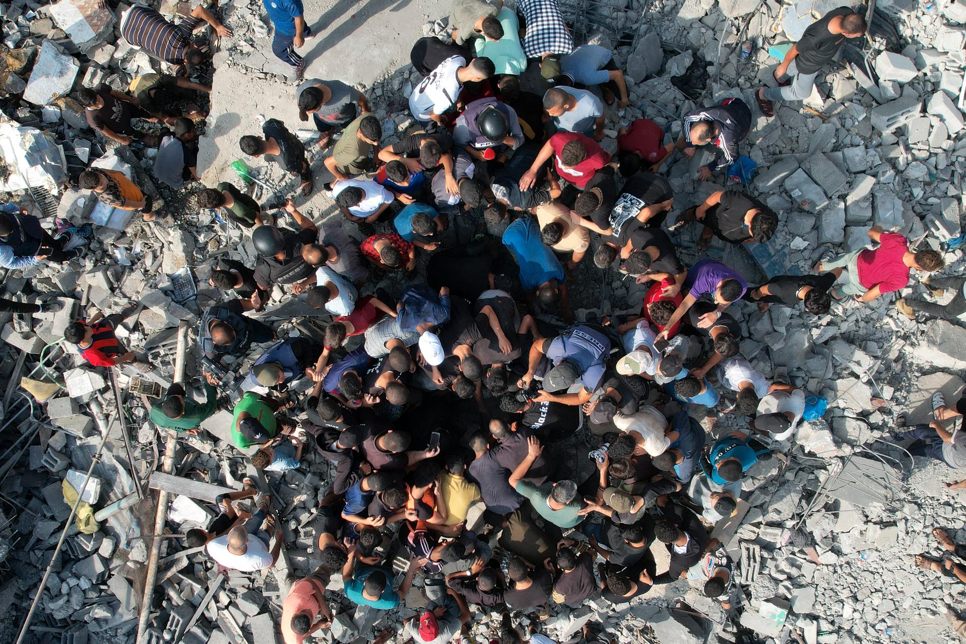 Överlevande söker igenom rasmassor efter israeliska raketanfall på Gazaremsan under söndagen.