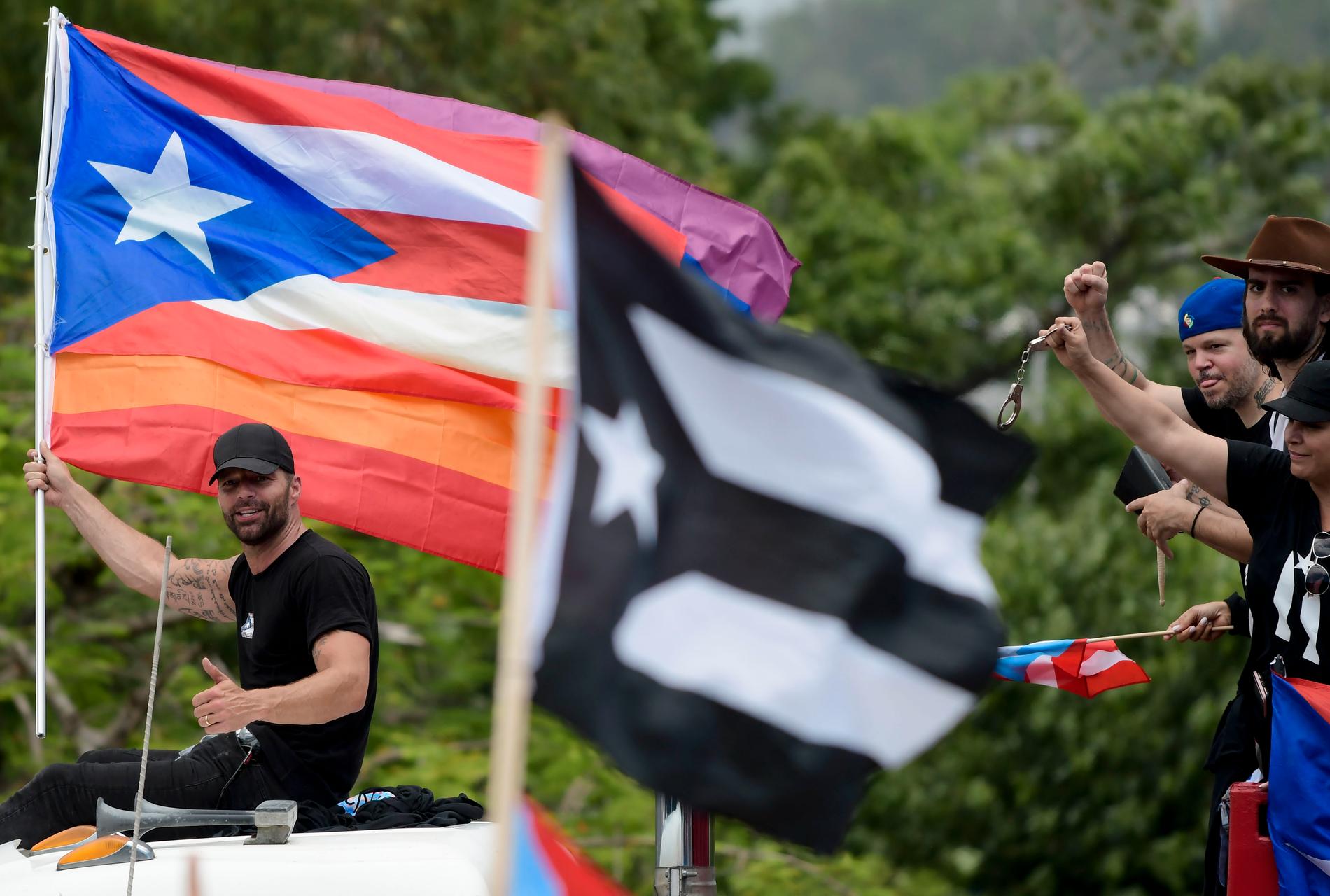 Artisten Ricky Martin håller en puertoricansk flagga under måndagens demonstration.