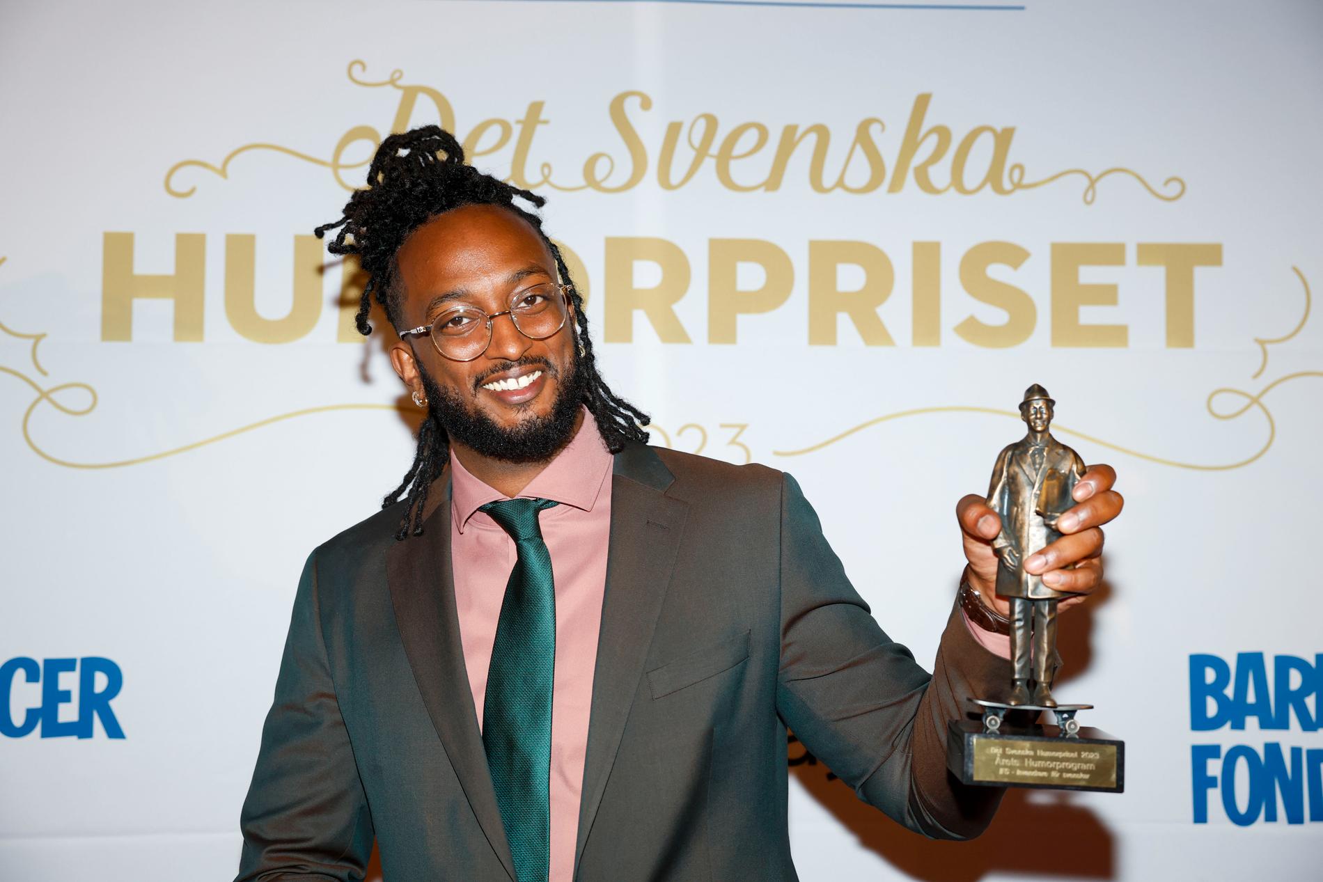 Ahmed Berhan tar emot pris för Årets humorprogram för ”Invandrare för svenskar” på Barncancergalan - det svenska humorpriset, i oktober 2023.