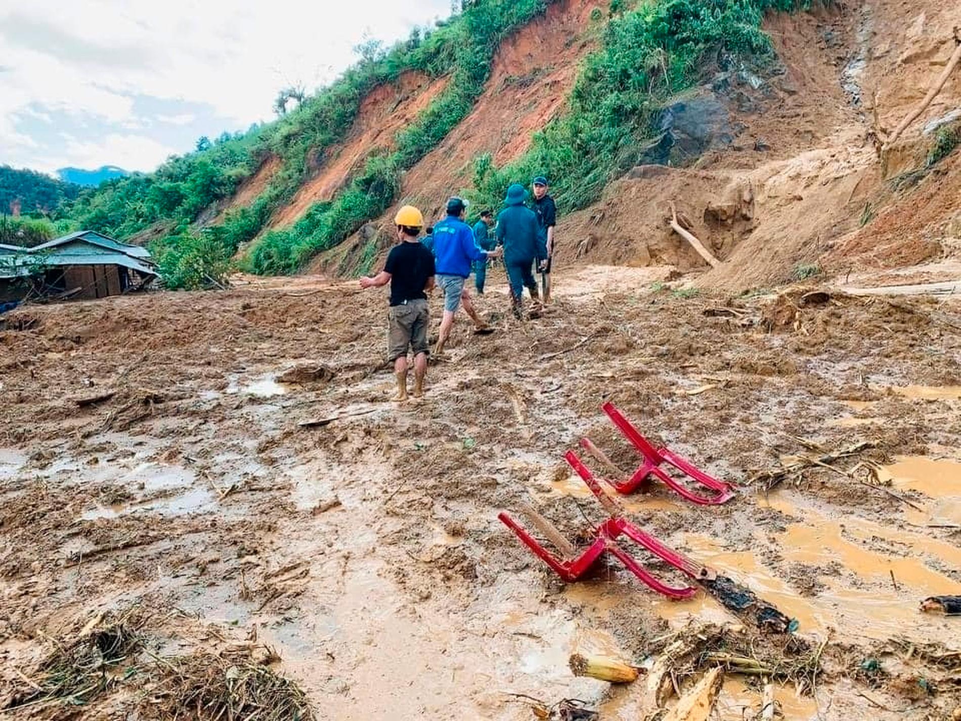 Bybor vadar genom lera efter ett jordskred i en by i distriktet Phuoc Loc i provinsen Quang Nam.