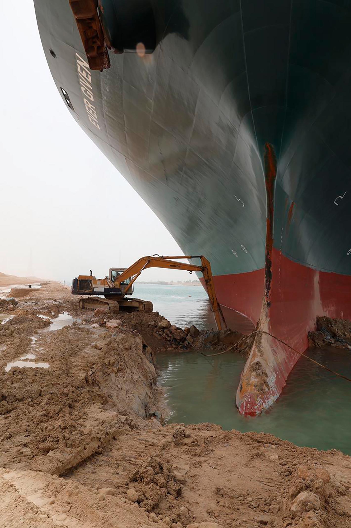 Grävskopor försöker få bort sand och gyttja runt skrovet på jättefartyget. 