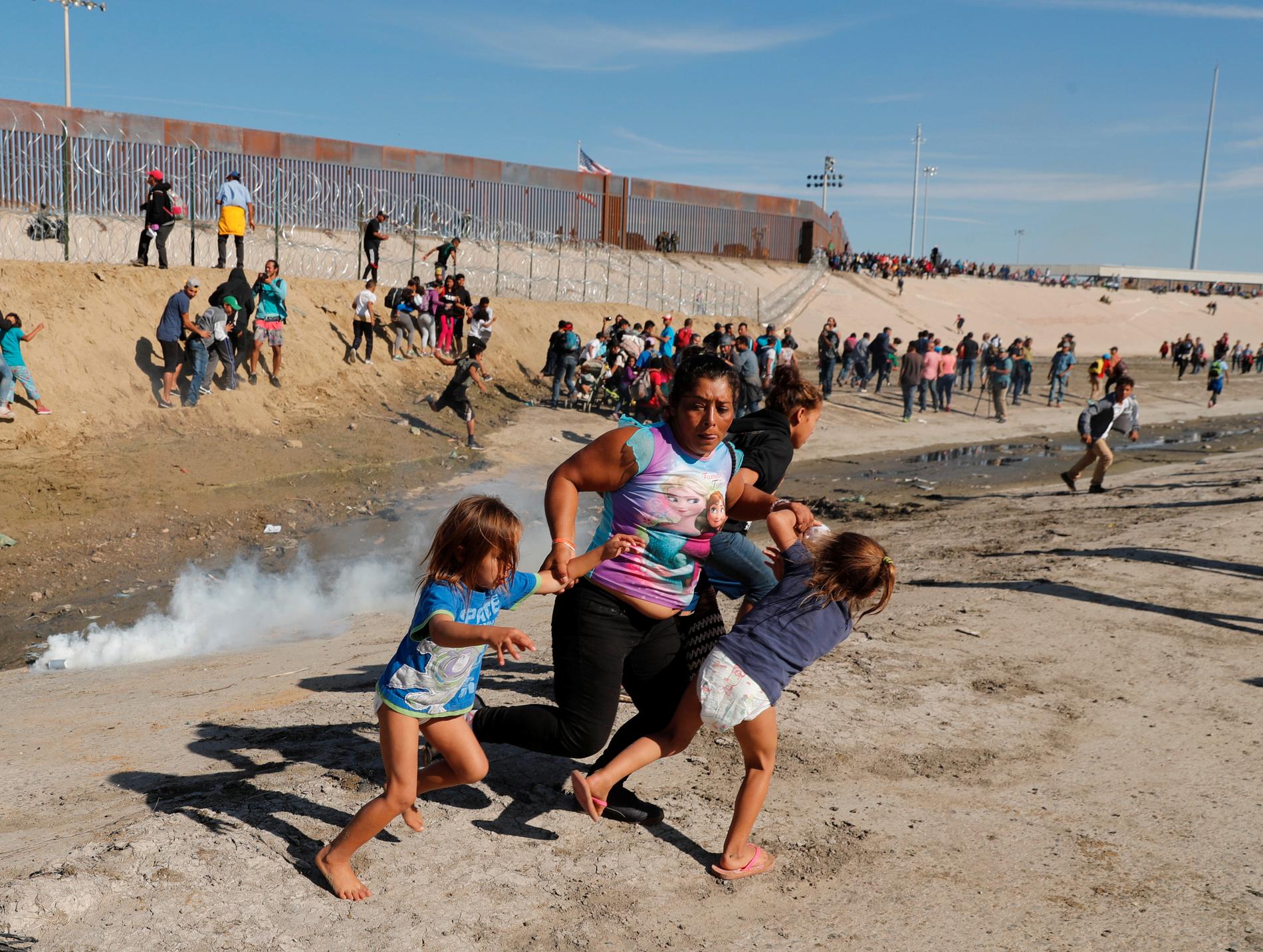 En familj springer från en tårgasbehållare som kastats över gränsen vid Tijuana. 