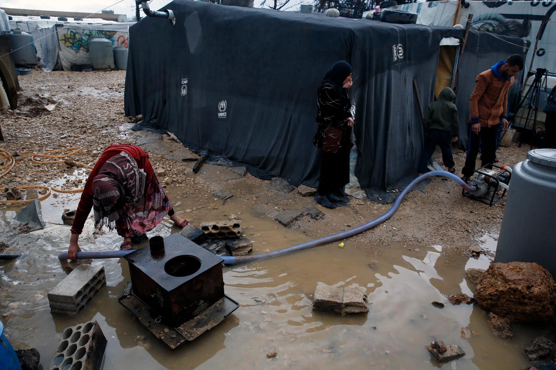 En flyktingfamilj från Syrien försöker pumpa bort vatten efter skyfall över det flyktingläger i staden Bar Elias i Libanon där de bor. Arkivbild.