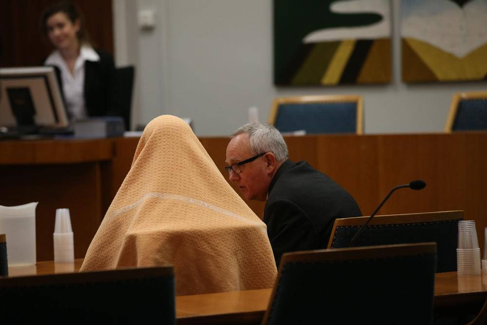 Under häktningsförhandlingarna i Lunds tingsrätt sitter han med kriminalvårdens senapsgula filt över huvudet.