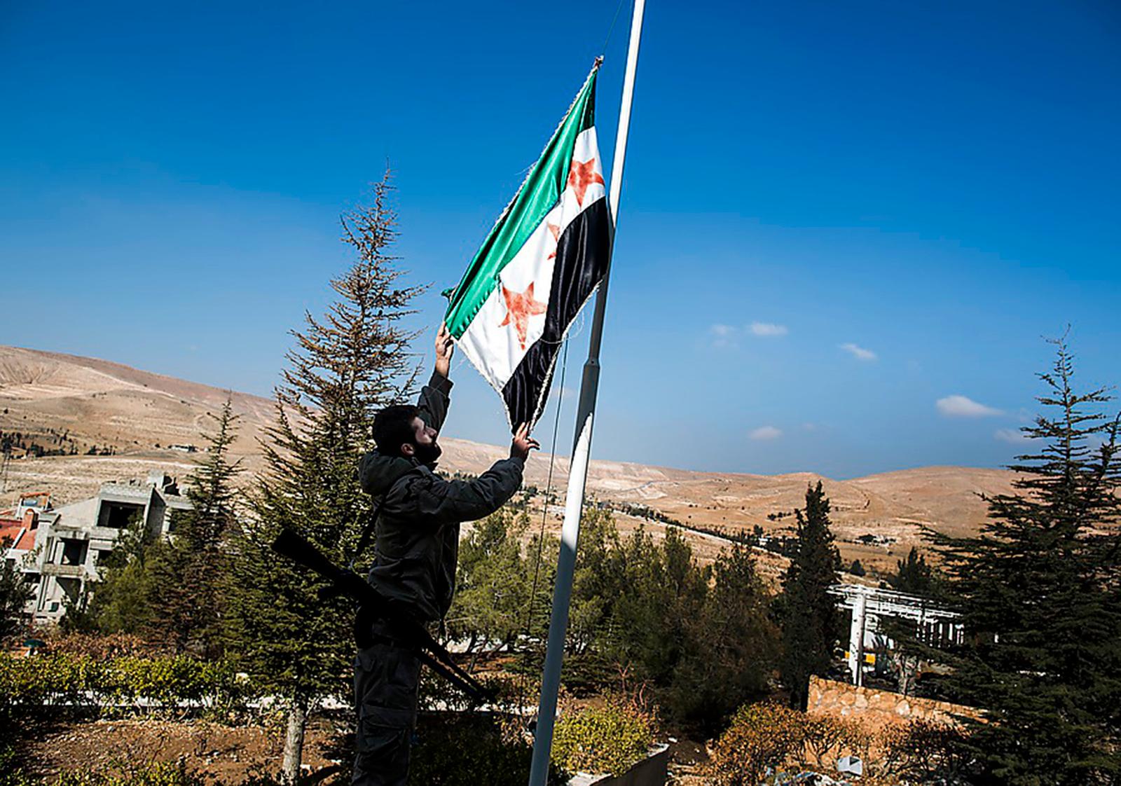 En man hissar Fria Syriska Arméns flagga i Maaloula.