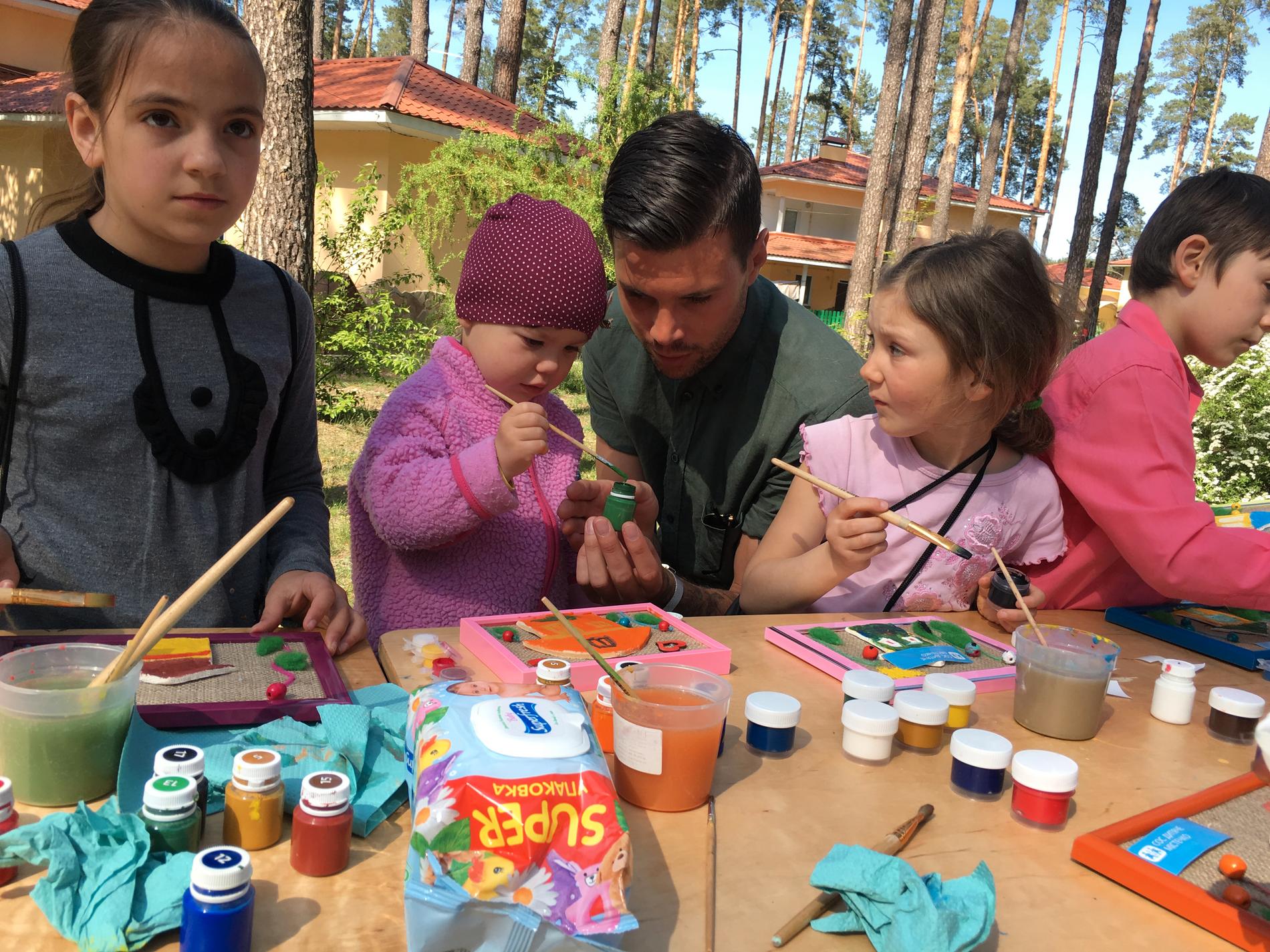 Robin Bengtsson tillsammans med några av barnen i barnbyn. Att måla används för att få barnen att uttrycka sina känslor och berätta hur de mår.