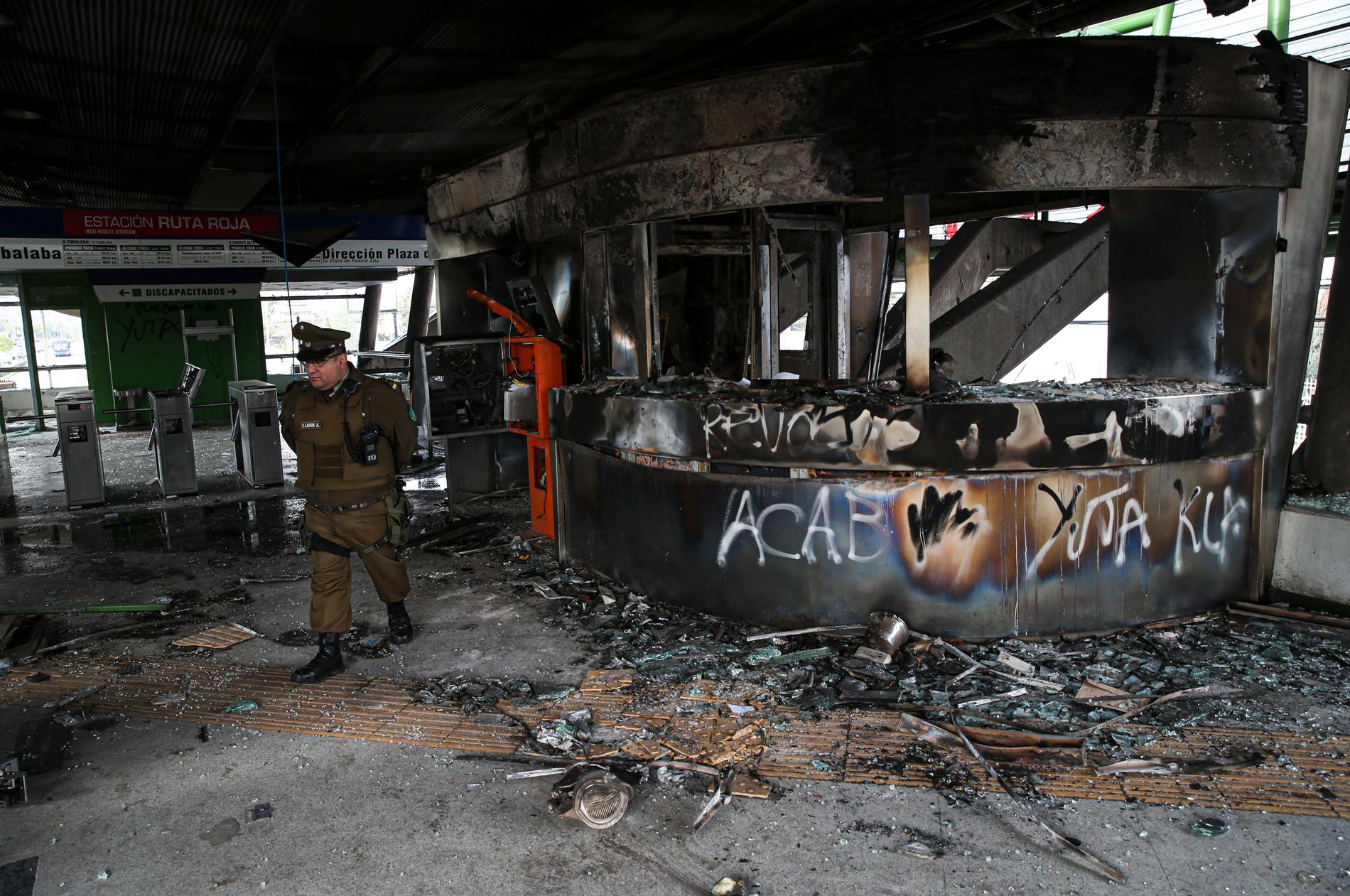 En polis vid en utbränd tunnelbanestation i Chiles huvudstad Santiago.