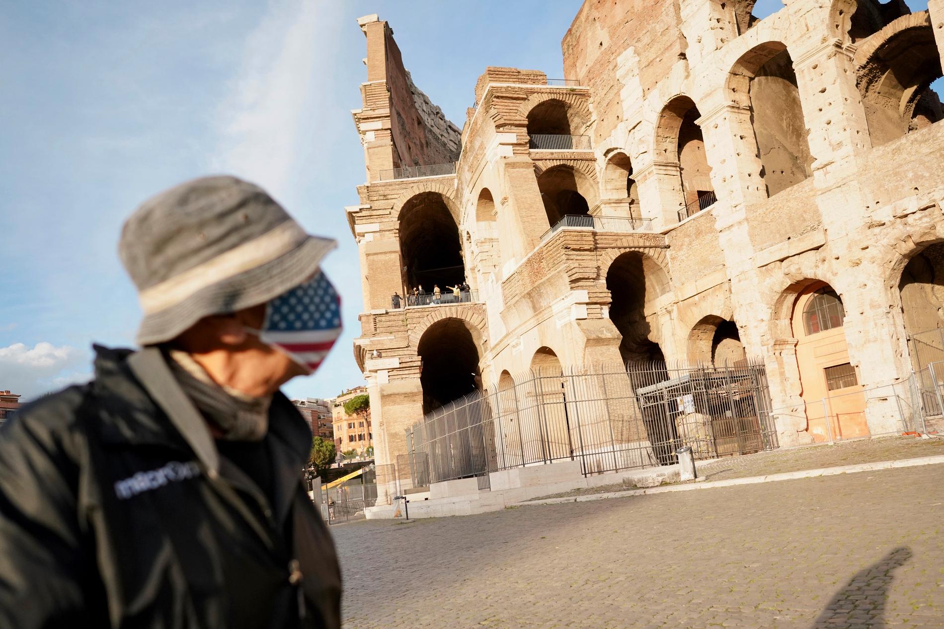 En man i mask utanför Colosseum i Rom.