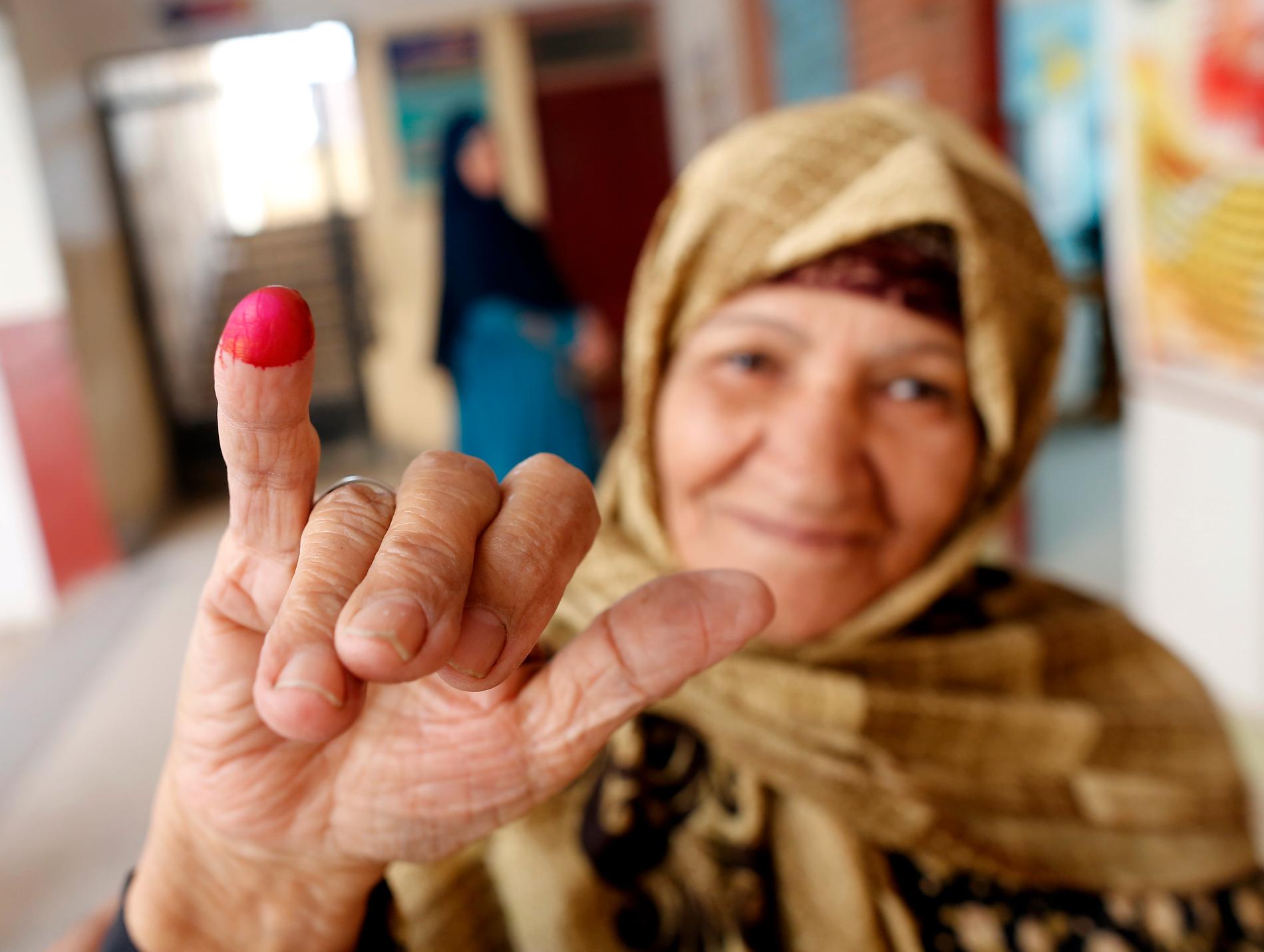 En kvinna visar upp sitt röda finger efter att ha röstat.