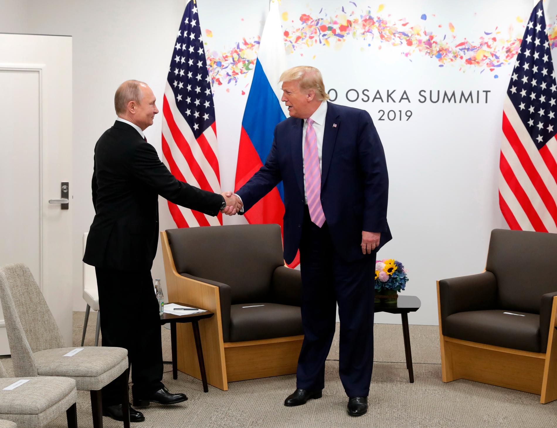 Vladimir Putin och Donald Trump skakar hand. 