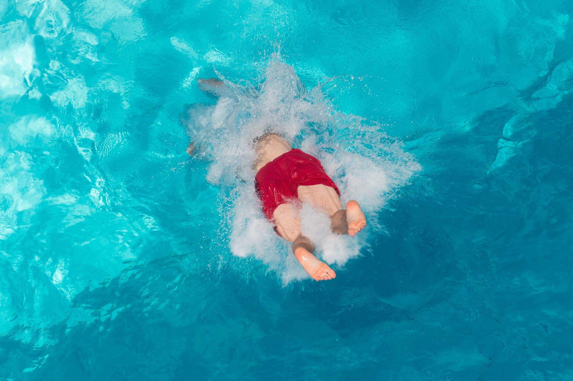 Ett barn hoppar i vattnet i en bassäng. Arkivbild.