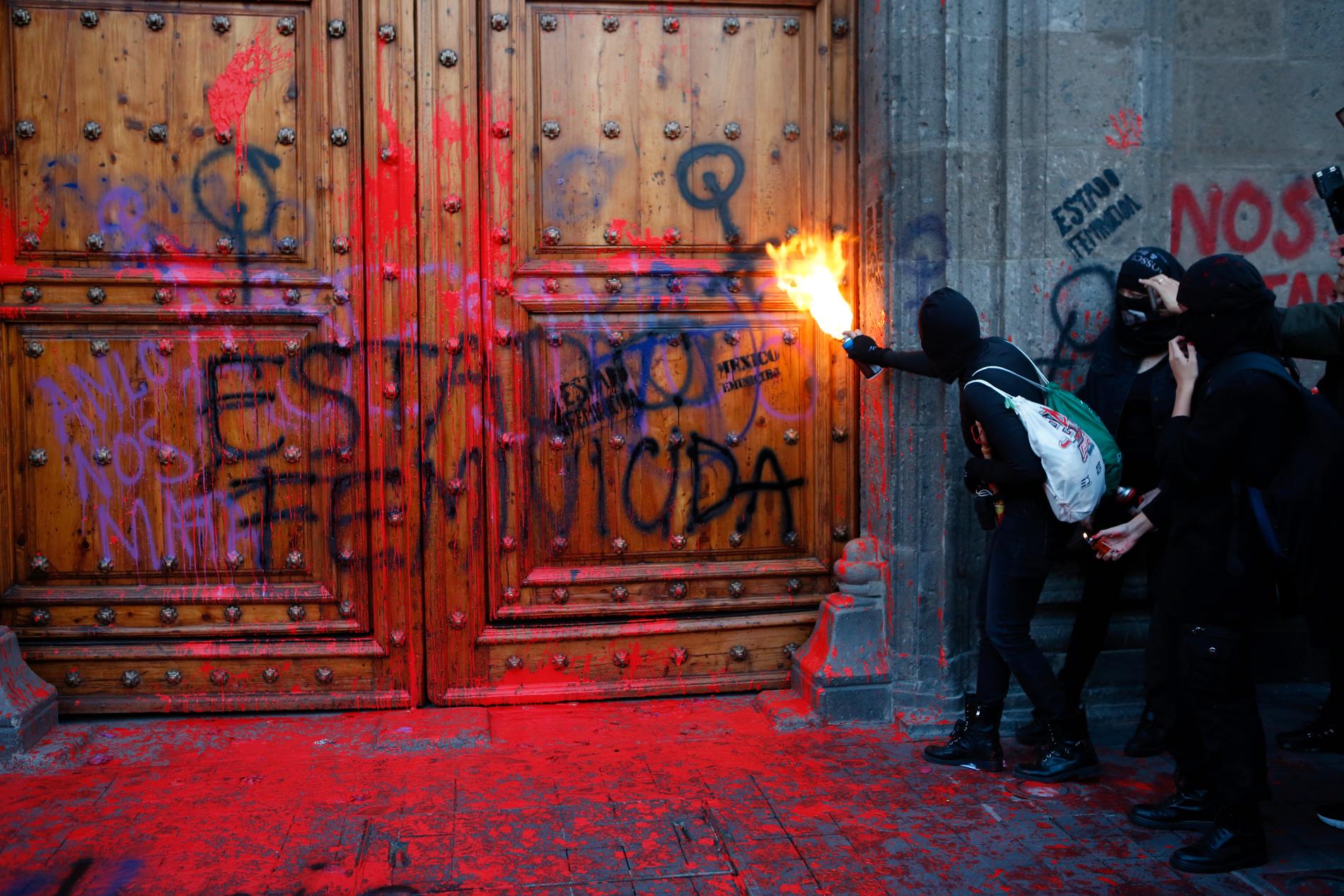 En maskerad deltagare i protesterna vid entrén till presidentpalatset i Mexico City.
