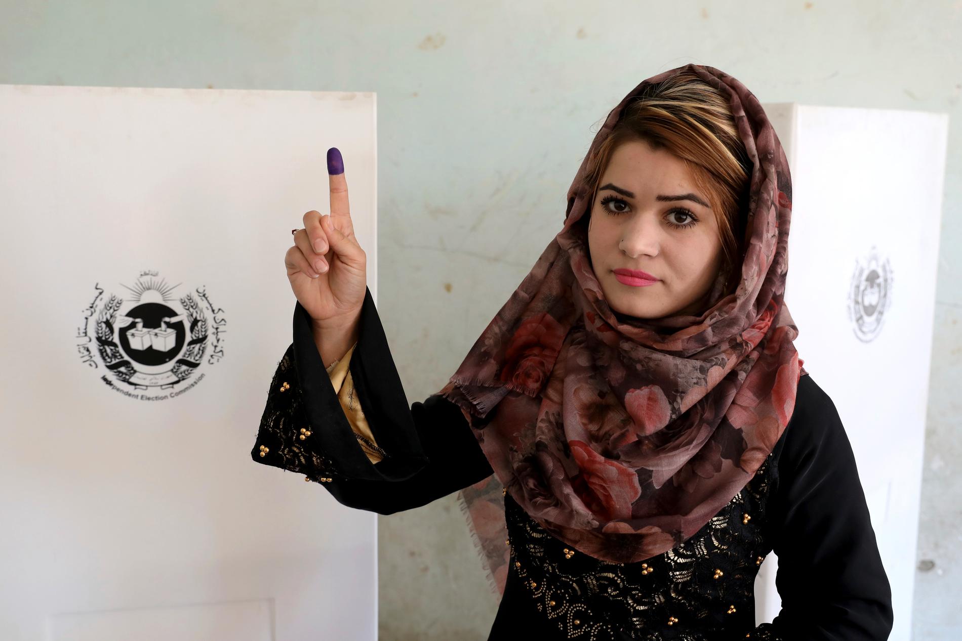 En kvinna visar upp sitt i bläck doppade finger, beviset för att hon röstat, vid en vallokal i Kabul.