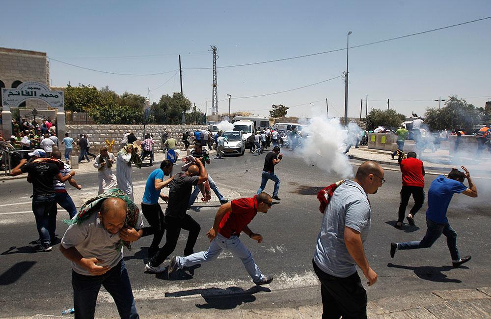 Palestinska demonstranter flyr undan polisens tårgas.