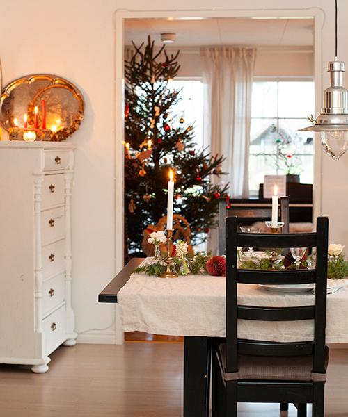 Att ha en riktig gran är en självklarhet för familjen Liljeqvist. Vacker matbordsdukning i beige, vitt och grönt. Adventsljusstaken får ett vackert sken med mässingsbrickorna som bakgrund.