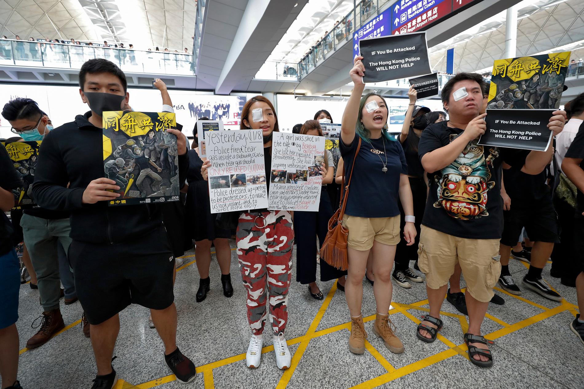 Många demonstranter bär lapp för ögat i ankomsthallen på Hongkongs internationella flygplats. Uppgiften om att polisens projektiler allvarligt skadat en kvinnas öga väcker vrede.