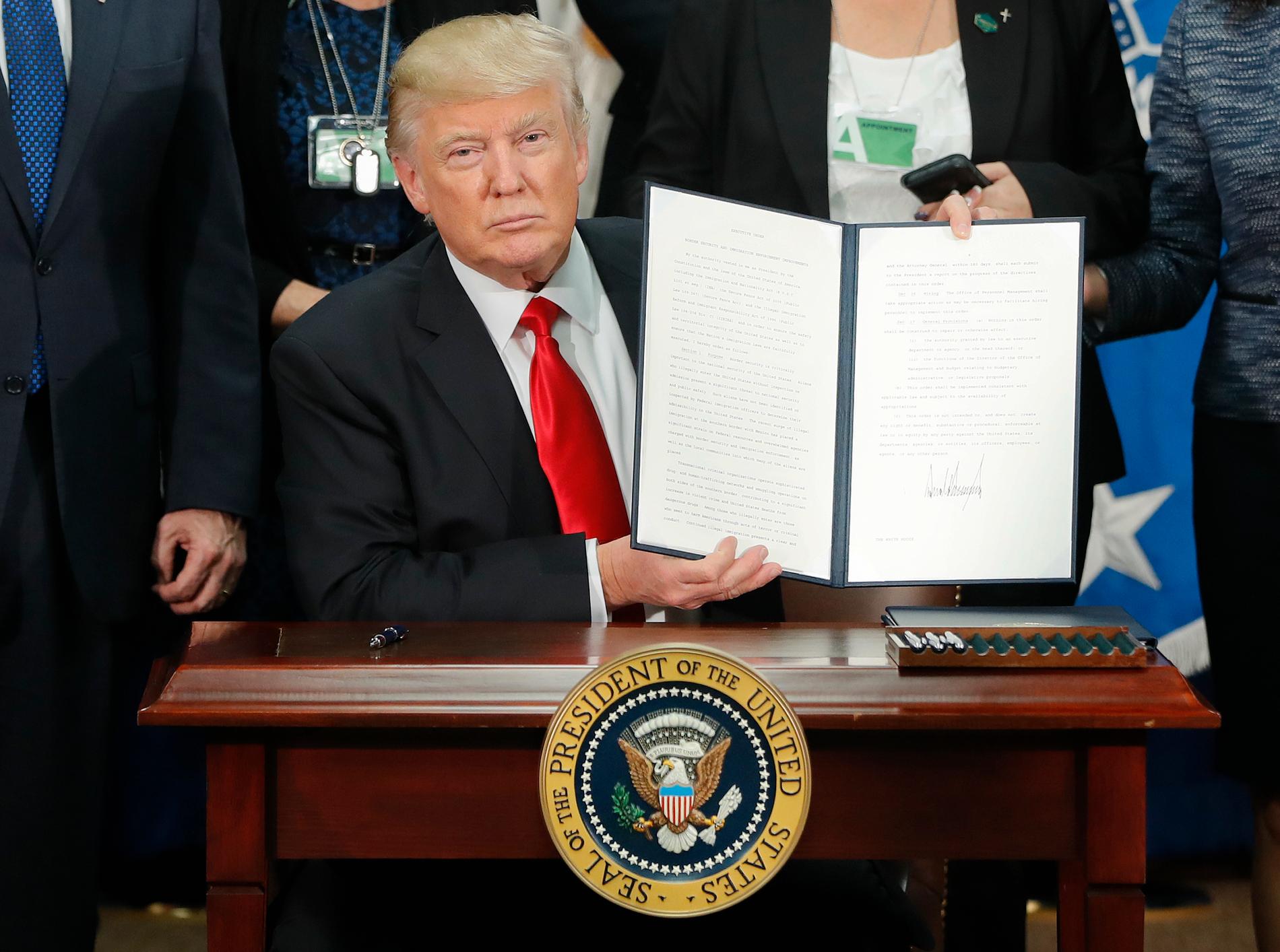 Donald Trump håller upp en underskriven exekutiv order.