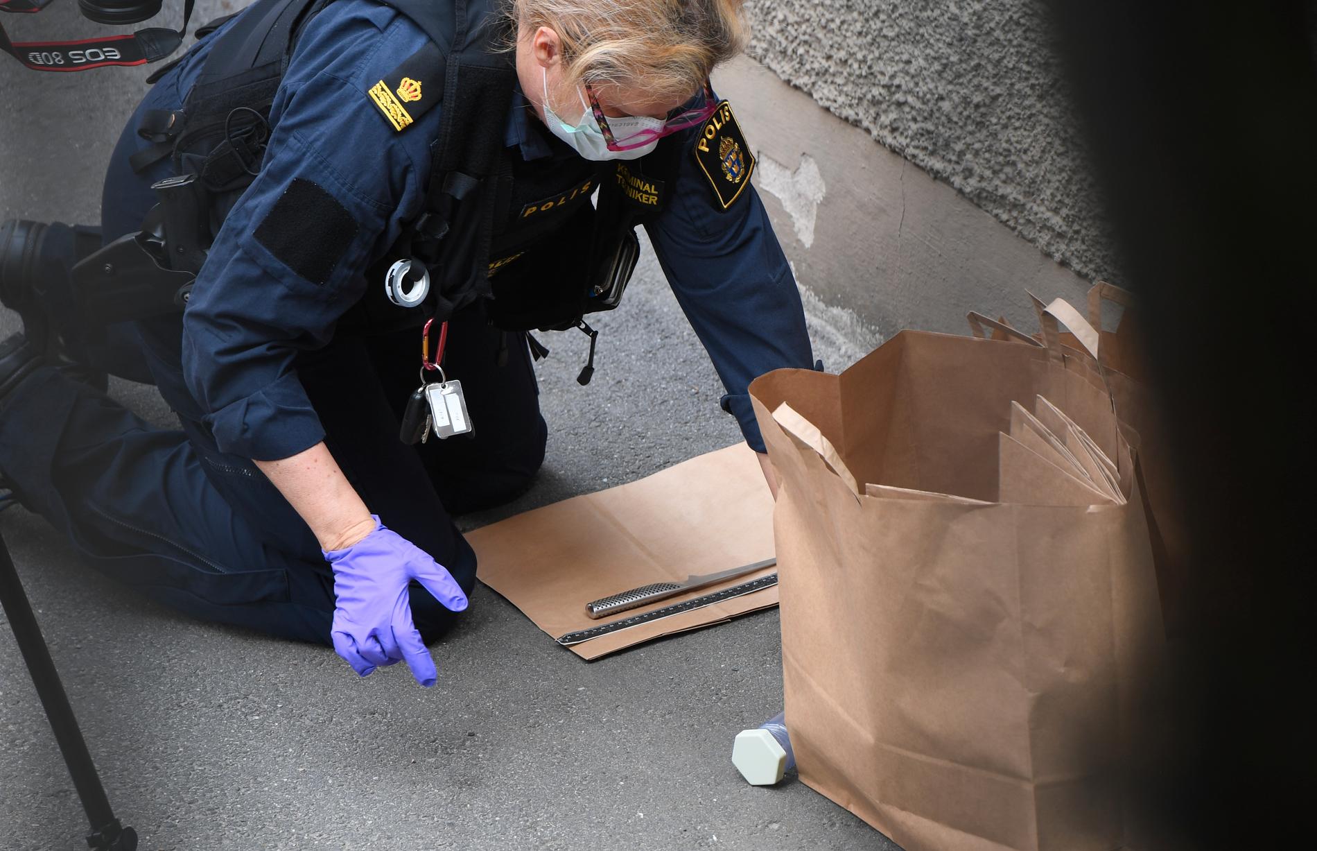 Polisens tekniker undersöker en kniv som hittats på platsen för överfallet