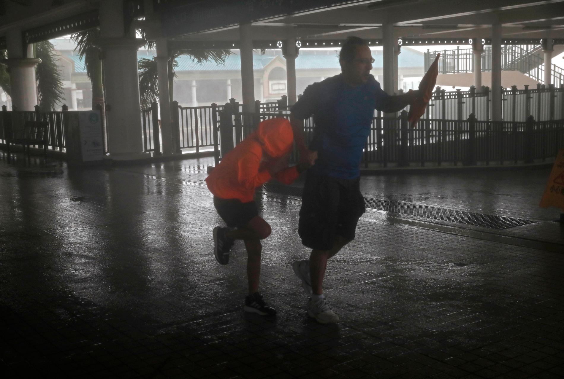 En man och en flicka kämpar mot de starka vindarna vid Victoria Harbour i Hongkong.