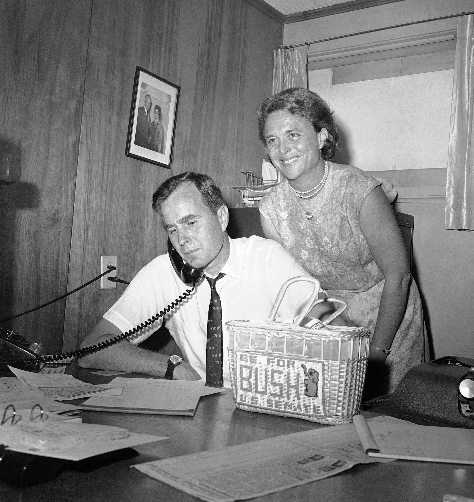 n this June 6, 1964, file photo George H.W. Bush, candidate for the Republican nomination for the U.S. Senate, gets returns by phone at his headquarters in Houston, as his wife Barbara, smiles at the news. 