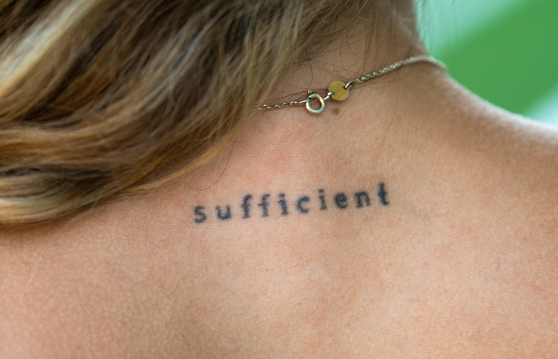 I nacken har 24-åringen från Gotland tatuerat in texten sufficient som betyder tillräcklig på engelska.