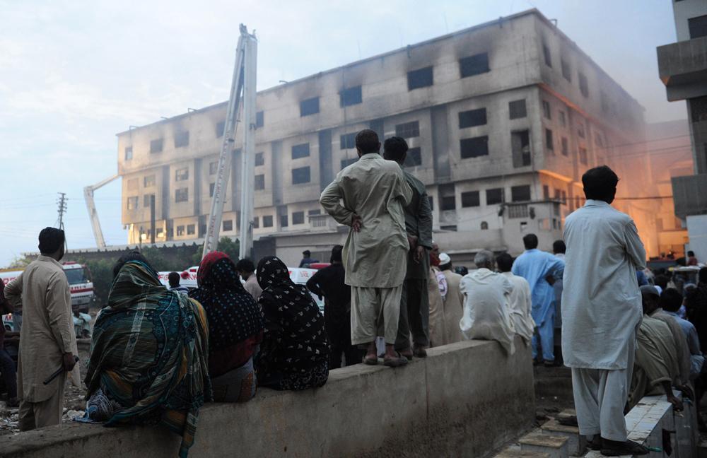 Invånare i Karachi betraktar förödelsen efter branden i klädfabriken.