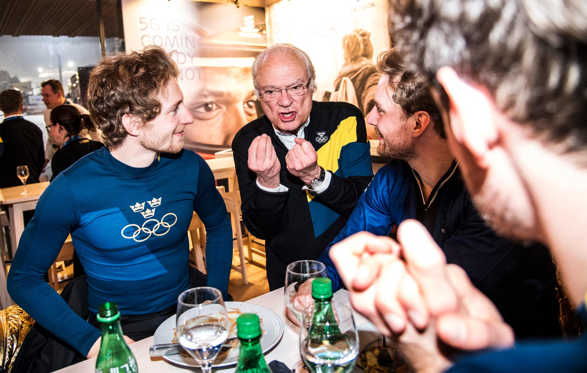 Samtidigt som skidskyttarna Peppe Femling, Jesper Nelin, Sebastian Samuelsson och Fredrik Lindström firar sitt OS-guld med köttbullar och lingonsylt så gratuleras de av en ivrig kung Carl XVI Gustaf i ”Sweden arena” i Pyeongchang. 