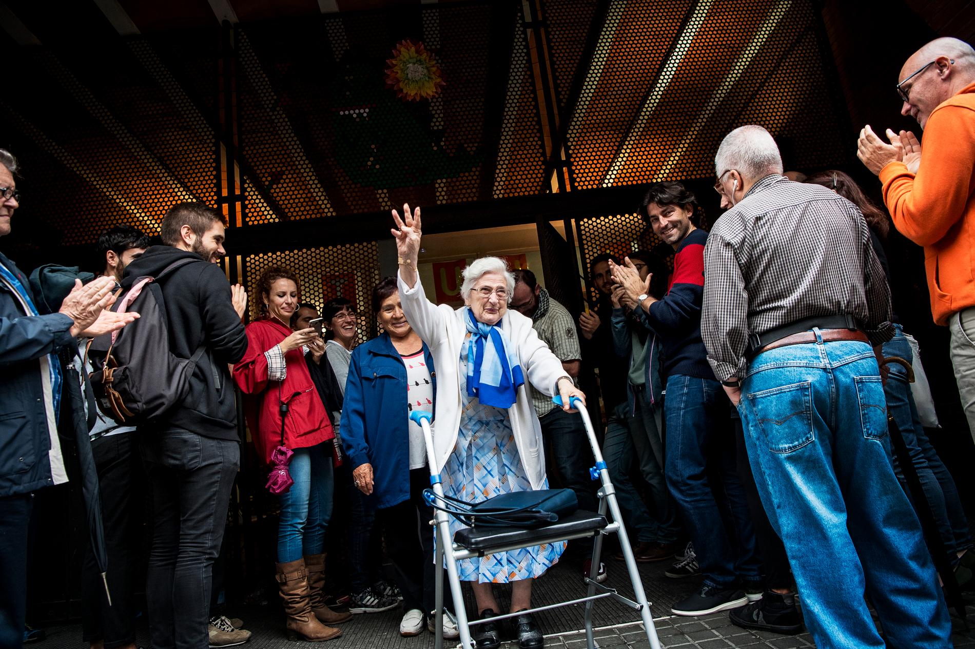 En äldre kvinna som lämnar röstningslokalen möts av jubel från människorna utanför.